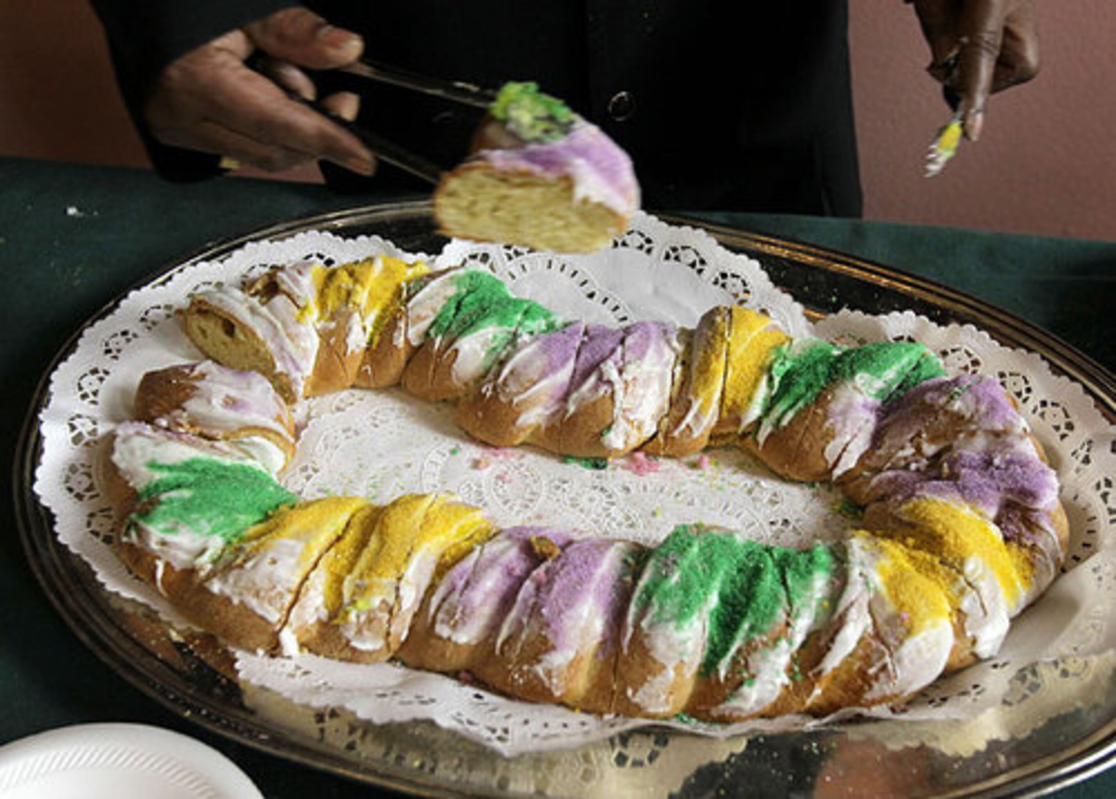 A worker distributes a slice of traditional Mardi Gras king cake during a ceremony to mark the beginning of carnival season in New Orleans, Thursday, Jan. 6, 2011.