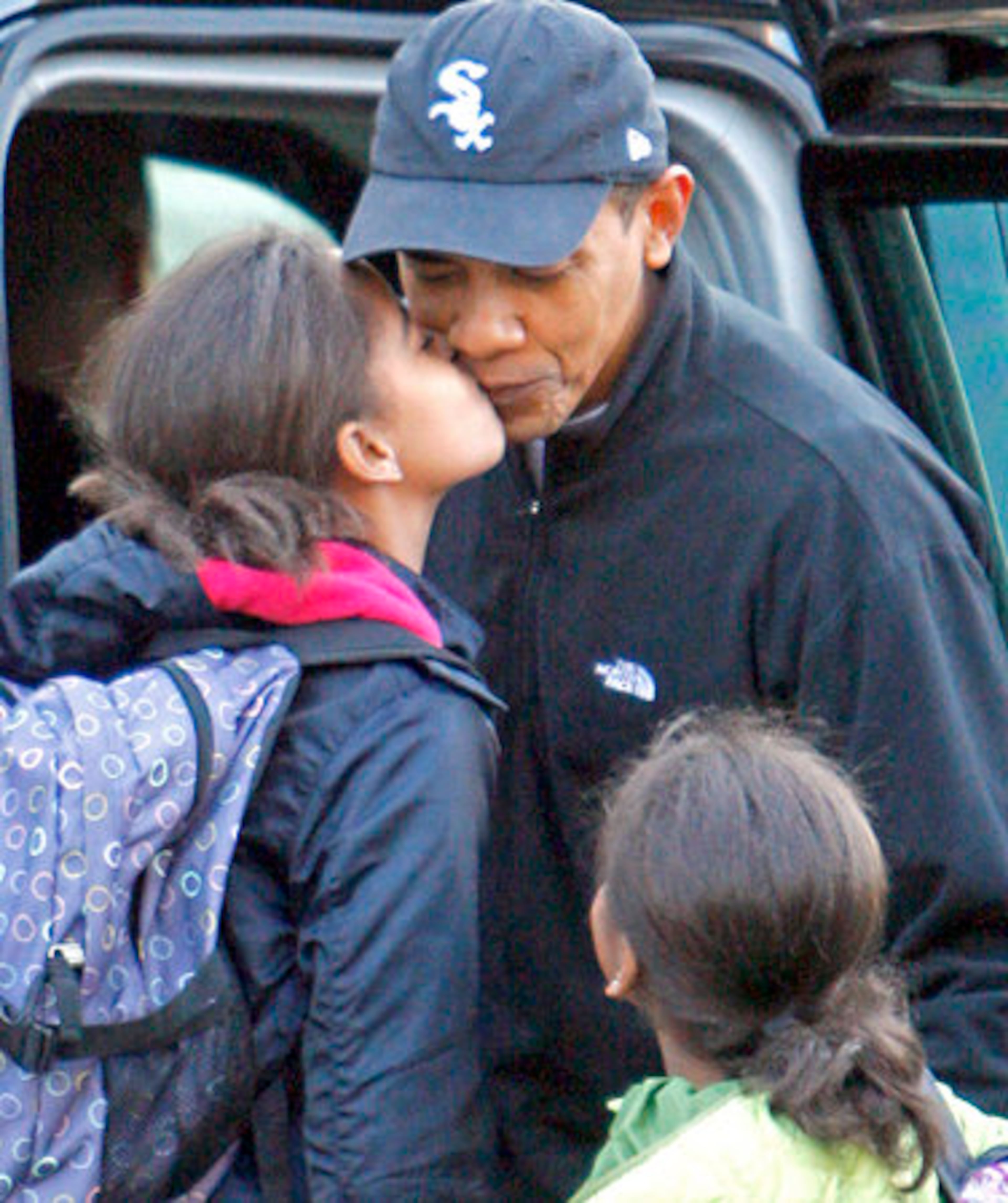 President-elect Obama, gets a kiss from his daughter Malia, as Sasha watches.