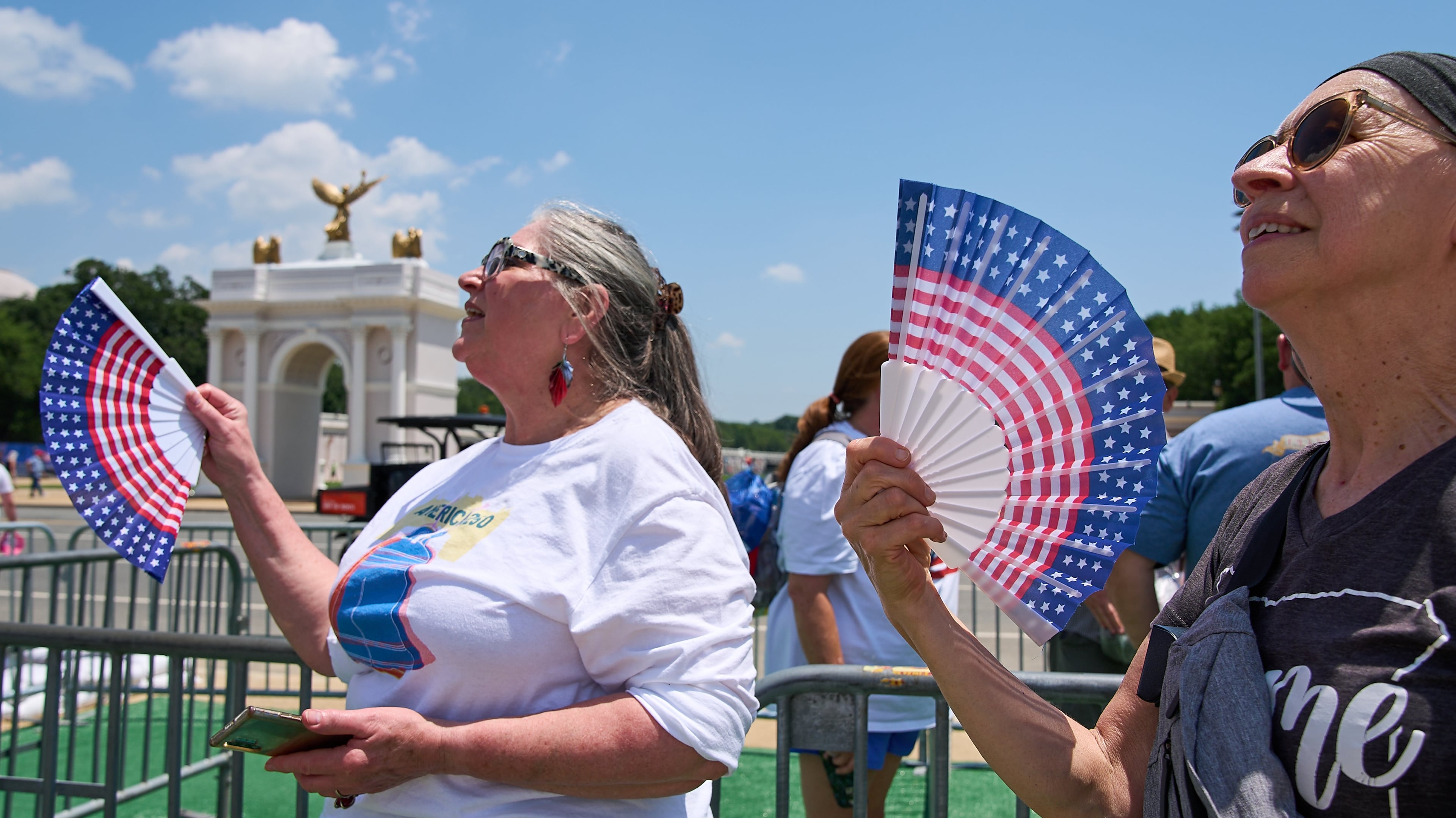 FILE - Mickelina Papotto, of Salem, Ore., left, and Lorie Odegaard, of Gaithersburg, Md., fan themselves while waiting in line for the ferris wheel at the Great American State Fair on the National Mall, July 1, 2026, in Washington. (AP Photo/Jacquelyn Martin)