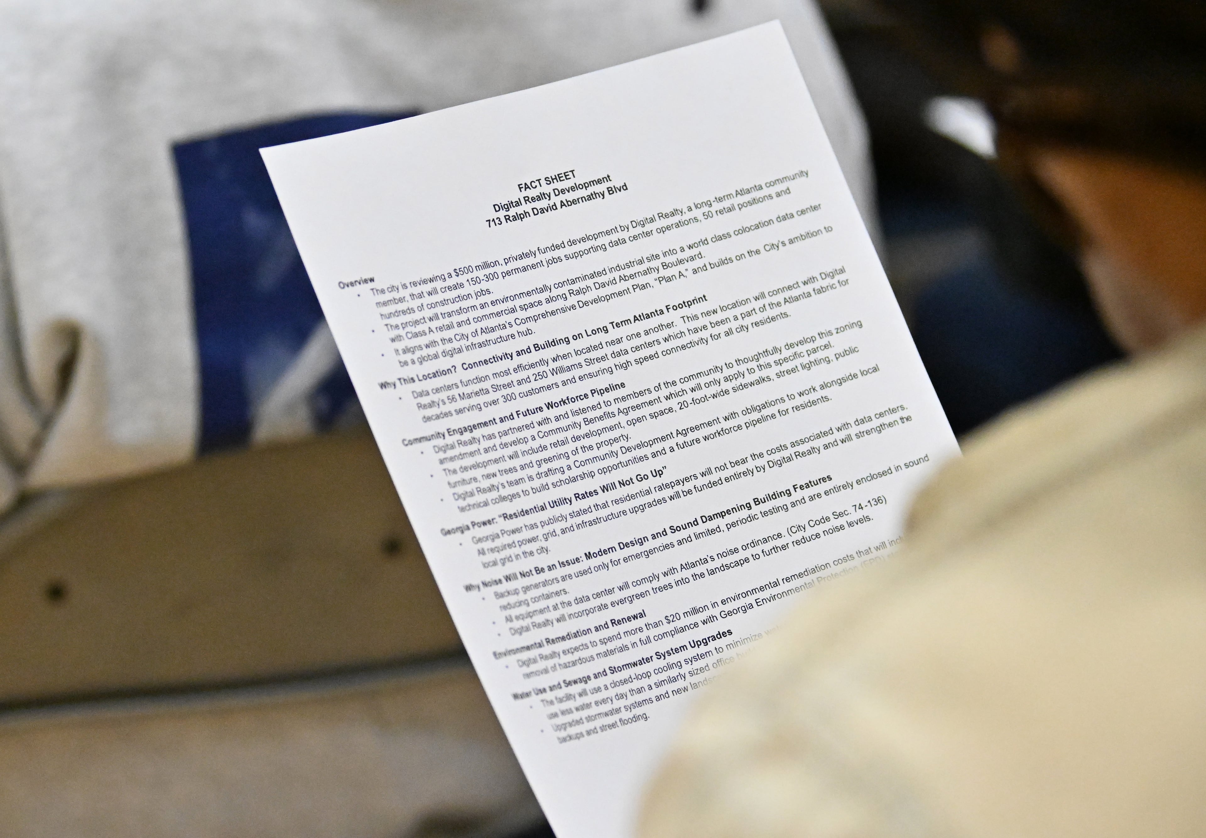 An attendee holds information paper as she listens to a presentation during a town hall by NPU-V and Digital Realty to discuss a planned data center in Atlanta at Dunbar Elementary School, Thursday, March 19, 2026, in Atlanta. (Hyosub Shin/AJC)
