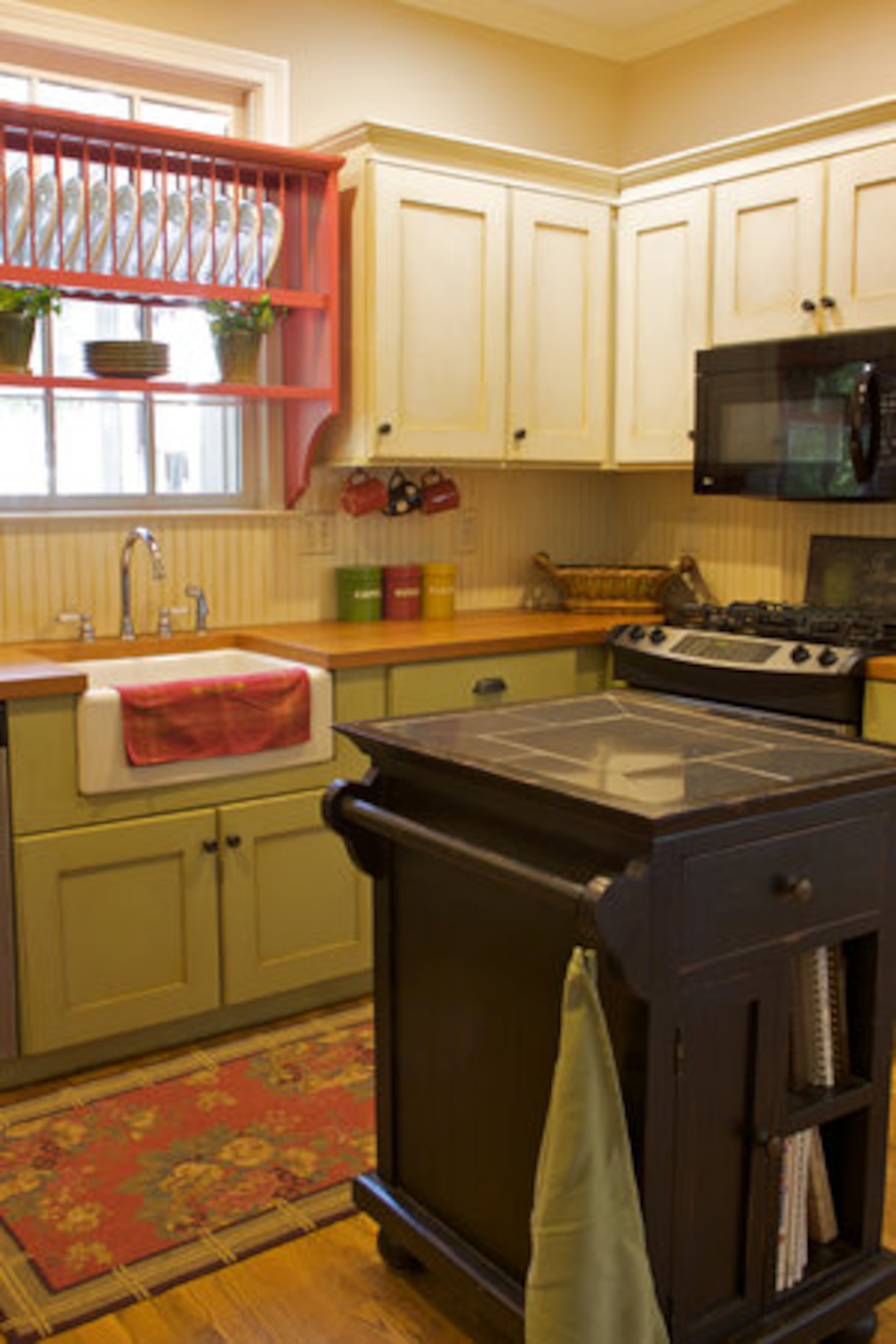 The kitchen received a makeover including a fresh coat of paint along with the installation of a farmhouse sink and reclaimed heart pine countertops, which Laura Strickland believes offers a warmer feel than granite countertops.