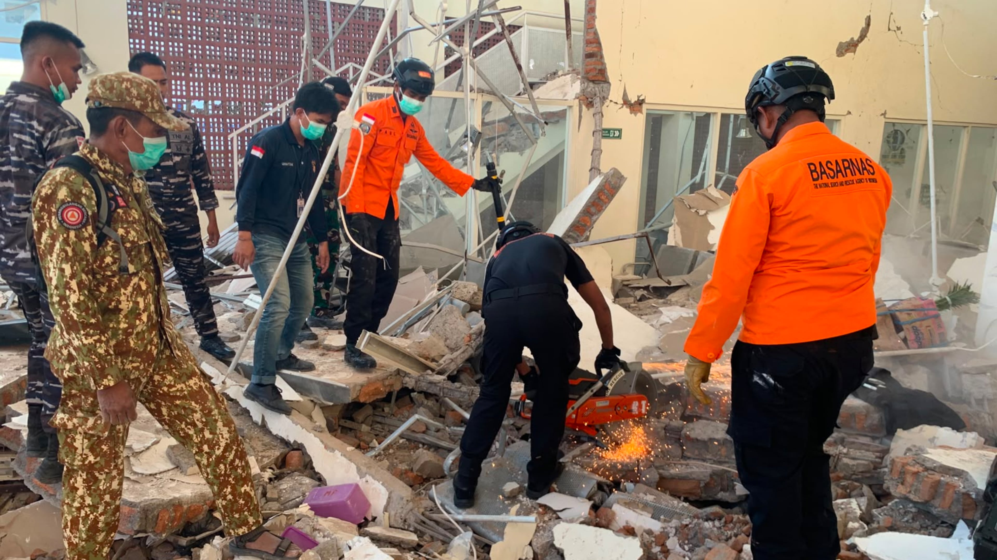 In this photo released by the Indonesian National Search and Rescue Agency (BASARNAS), rescuers attempt to clear debris at building damaged by an earthquake in Maumere, East Nusa Tenggara Province, Indonesia, Saturday, Aug. 15, 2026. (BASARNAS via AP)