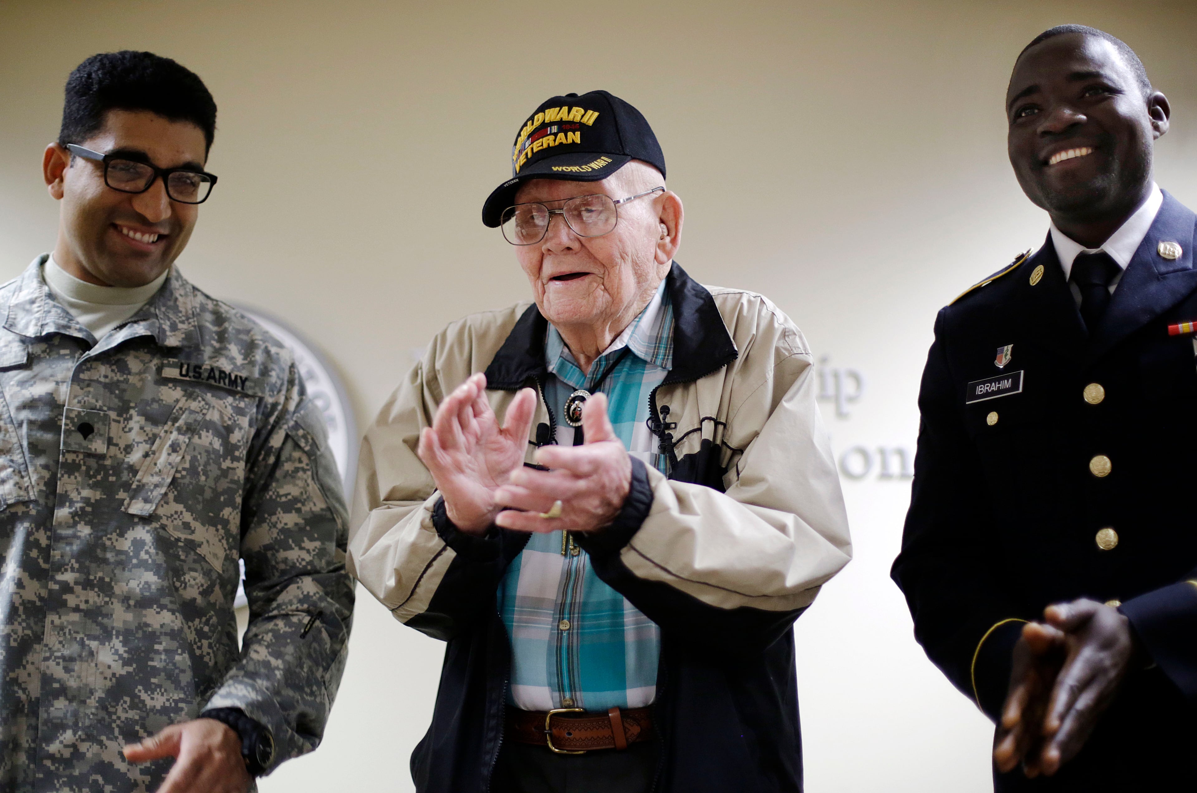 Ninety-four-year-old World War II veteran Sherwin Callander, center, applauds after a naturalization ceremony with U.S. Army Spc. Gulam Ali, left, originally from India, and U.S. Army Spc. Iddrisu Ibrahim, originally from Ghana, right, Monday, June 2, 2014, in Atlanta.