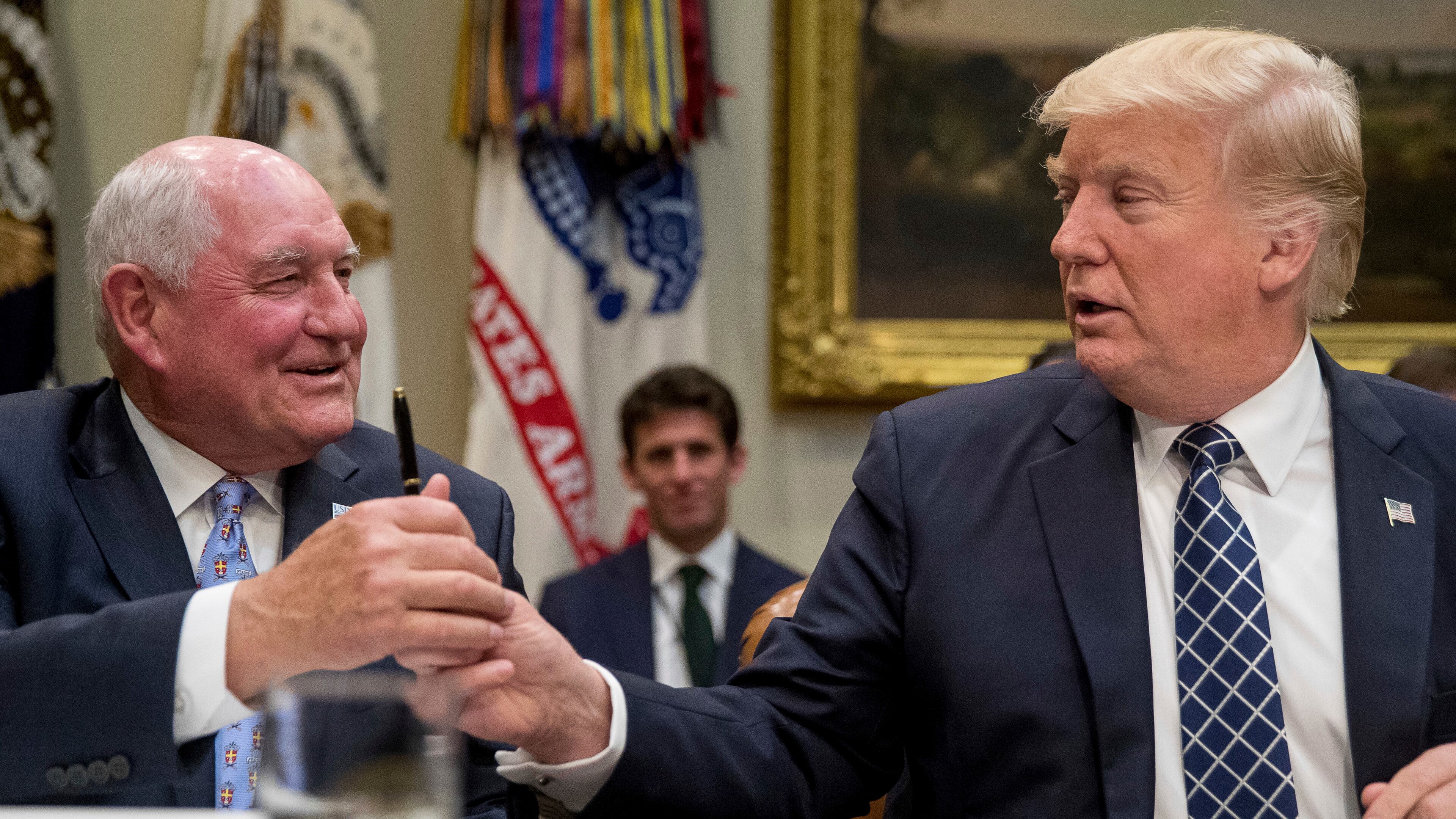 President Donald Trump hands a pen to Agriculture Secretary Sonny Perdue after signing an executive order during farmers' roundtable in the Roosevelt Room of the White House in Washington, Tuesday, April 25, 2017. (AP Photo/Andrew Harnik)
