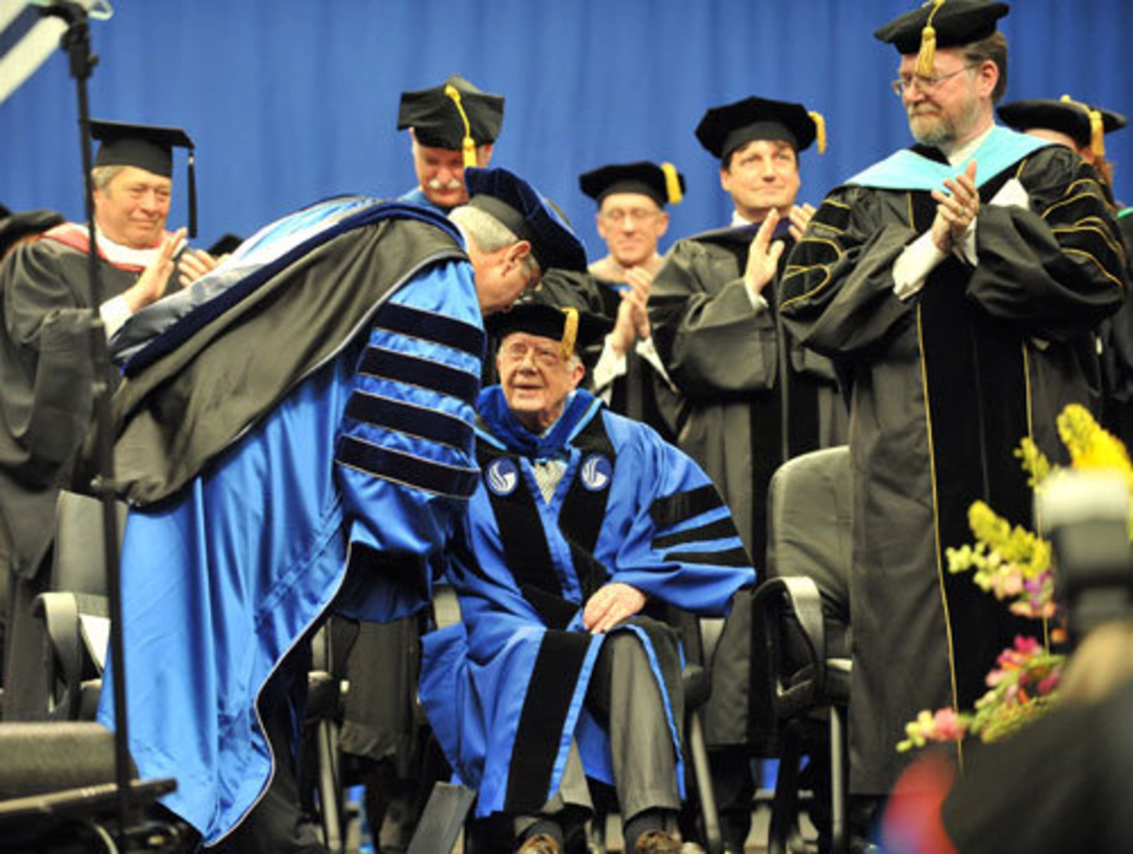 Former President Jimmy Carter, center, is greeted by Mark P. Becker, foreground left, President of GSU, after Carter's commencement address during the commencement ceremony for Georgia State University.