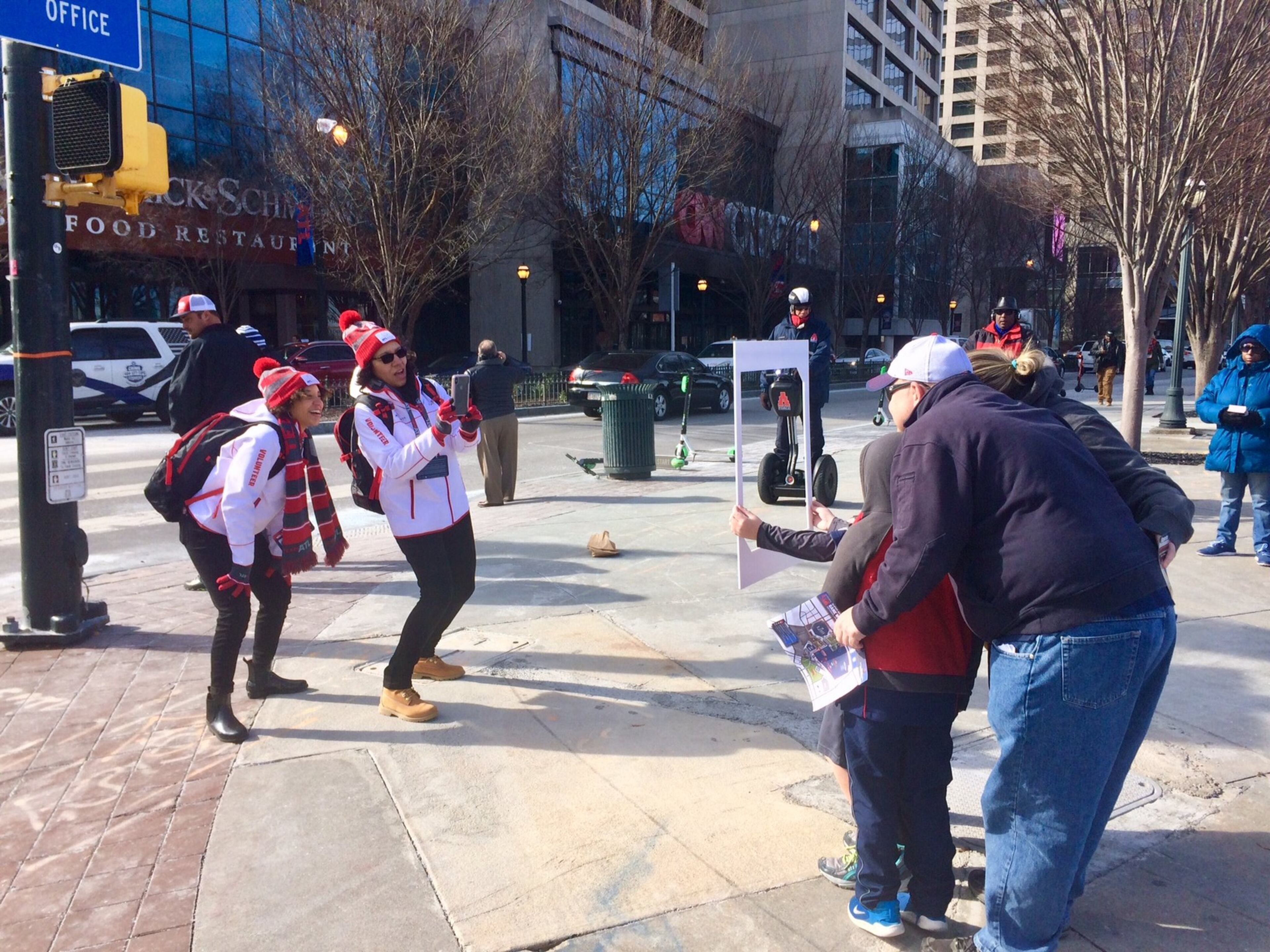 Super Bowl volunteers Lindsey Henry (left) and Lisa Pruitt frame a family of visitors for a street photo shoot in downtown Atlanta.