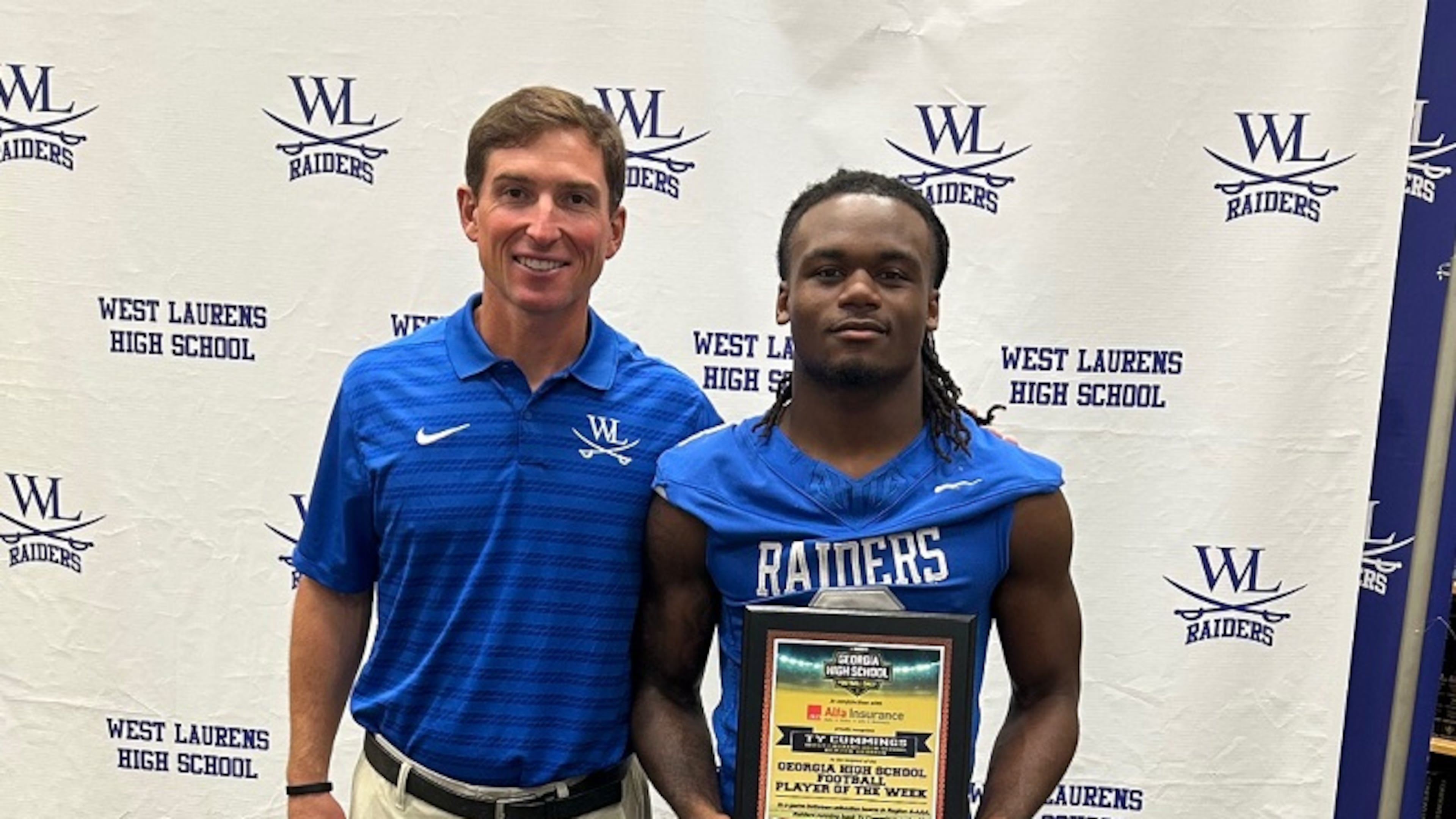 Ty Cummings, with West Laurens coach Kip Burdette, holds his AJC Varsity/GHSF Daily state player of the week plaque after a 224-yard rushing performance against Harlem on Friday, Sept. 19, 2025. Cummings rushed for an reported 615 yards and eight touchdowns Friday, Sept. 26, in a 70-55 victory over Baldwin. (Courtesy of Ted Langford)