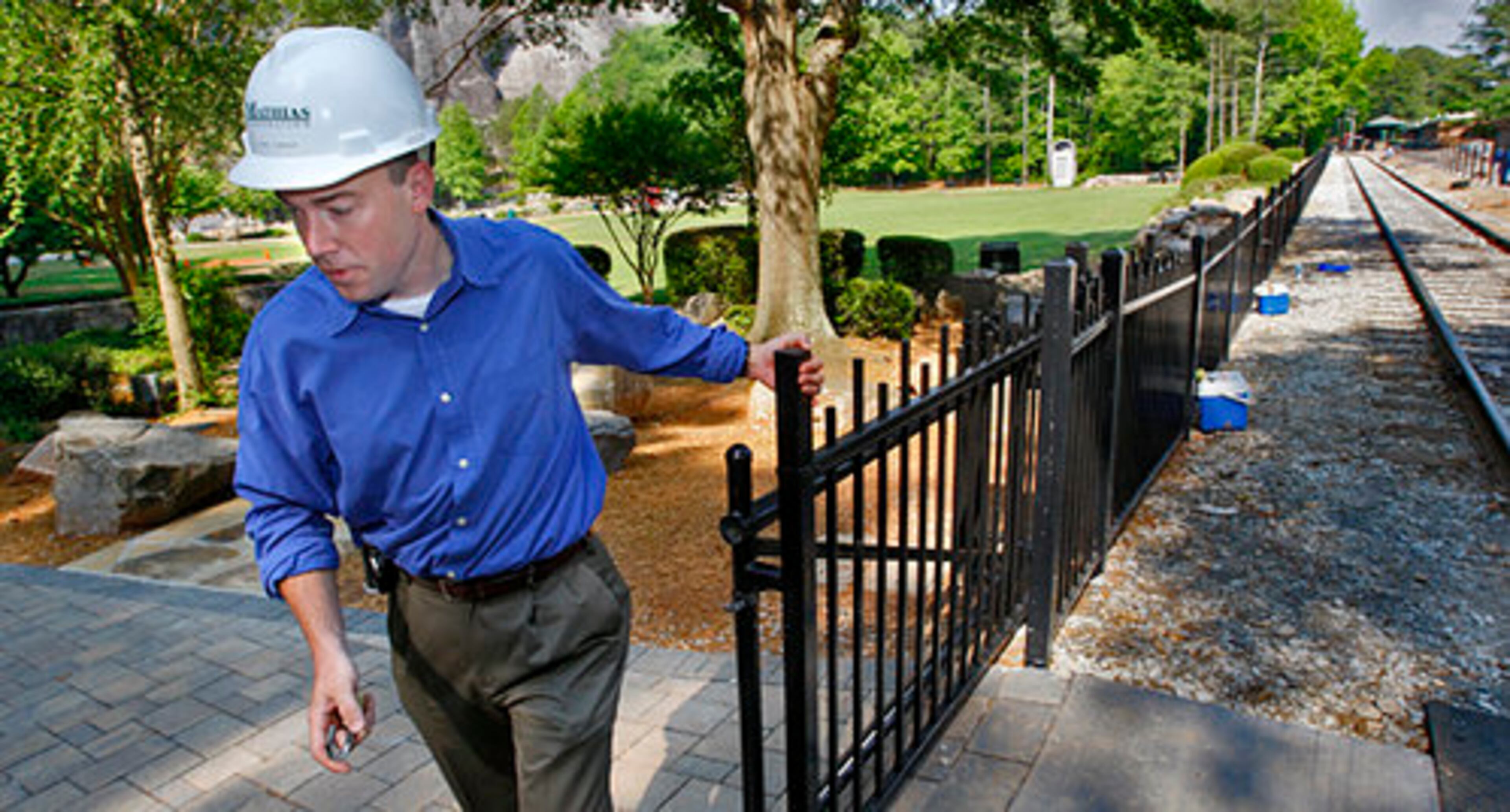 Project Manager, Paul Creasy closes rolling gate on the new fence that runs along the railroad tracks.