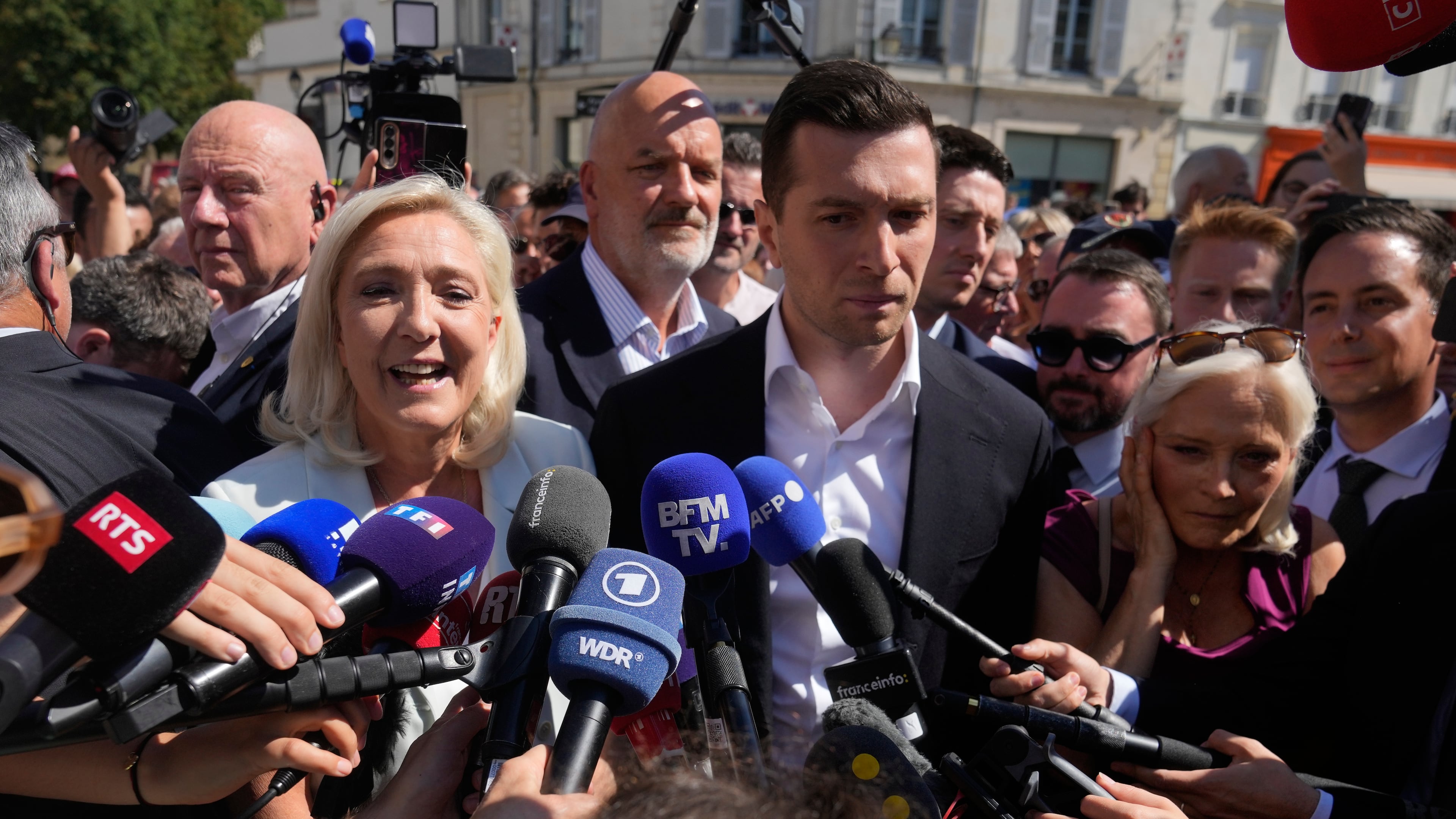 Far-right leader Marine Le Pen and Far-right party National Rally president Jordan Bardella answer journalists as they arrive to visit a market in La Fleche, western France Wednesday, July. 8, 2026. (AP Photo/Michel Euler)