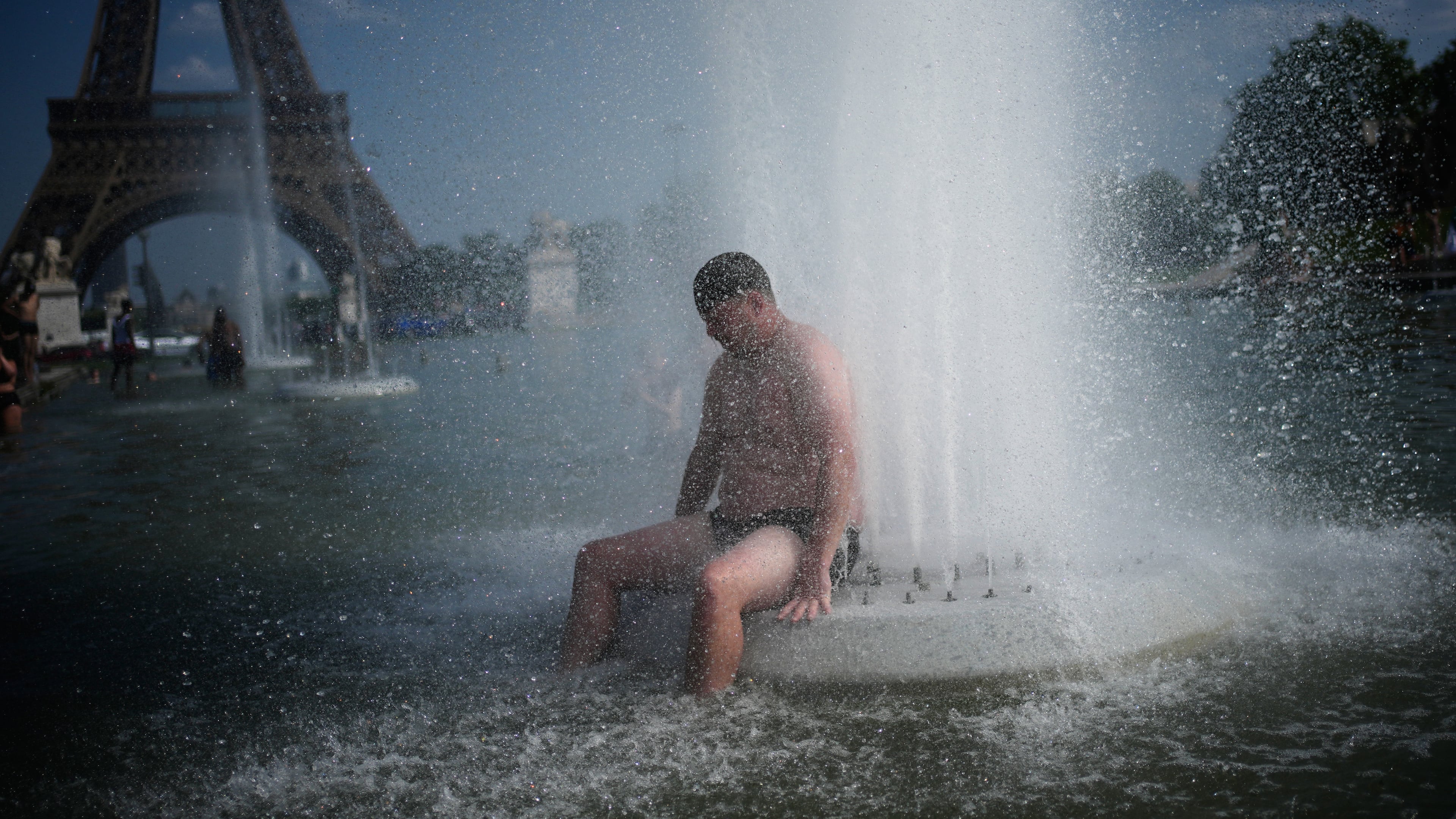 A person cools off at Trocadero fountain near the Eiffel Tower during a heat wave in Paris, Wednesday, June 24, 2026. (AP Photo/Christophe Ena)