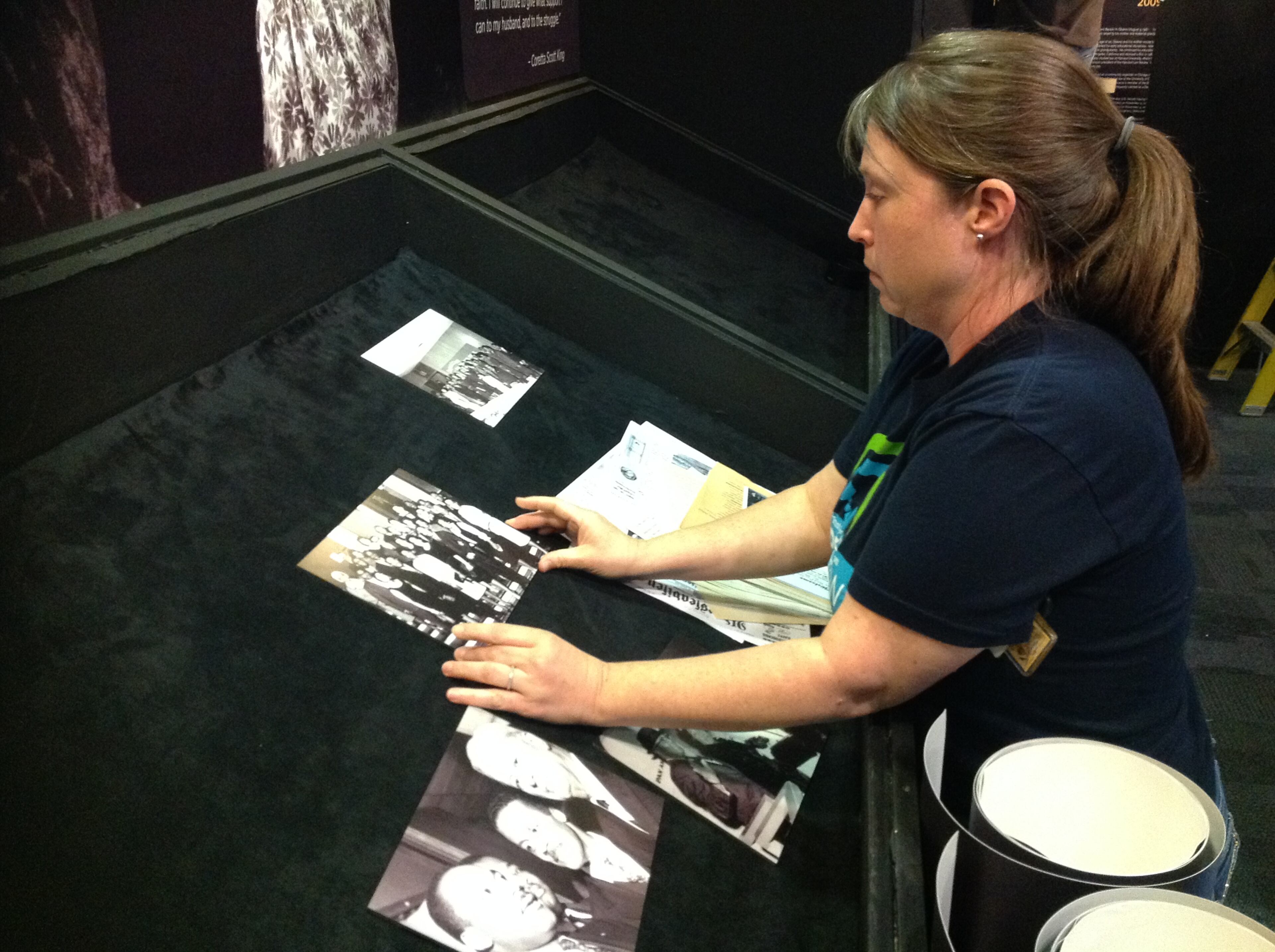 Leah Berry, a museum technician at the King Historic Site, installs photographs and documents that will be on display in the exhibit. Among them are photographs and reflections from his family when he won the Nobel Peace Prize.