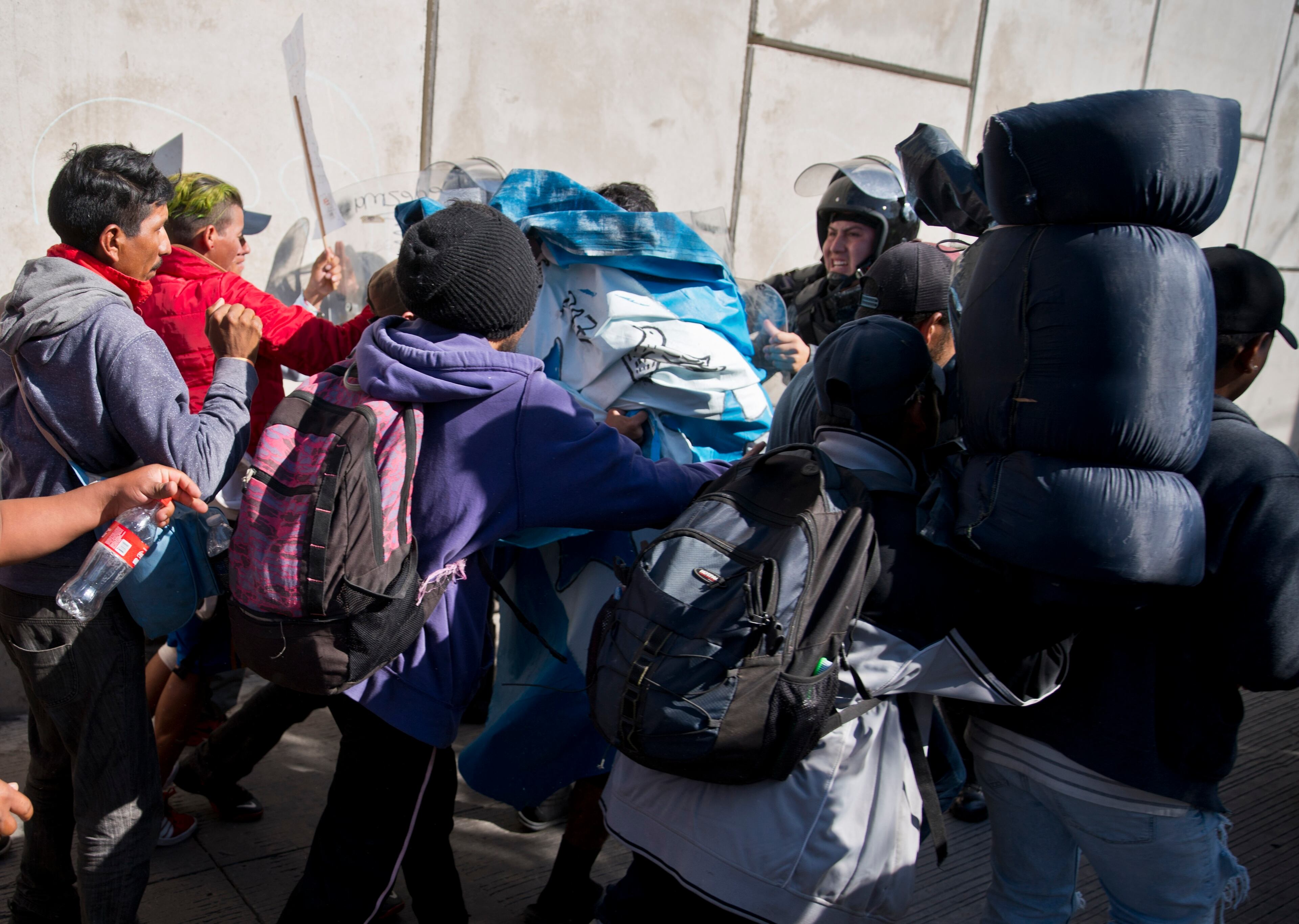 Migrants push past Mexican police at the Chaparral border crossing in Tijuana, Mexico, Sunday, Nov. 25, 2018, as they try to reach the U.S. The mayor of Tijuana has declared a humanitarian crisis in his border city and says that he has asked the United Nations for aid to deal with the approximately 5,000 Central American migrants who have arrived in the city. (AP Photo/Ramon Espinosa)