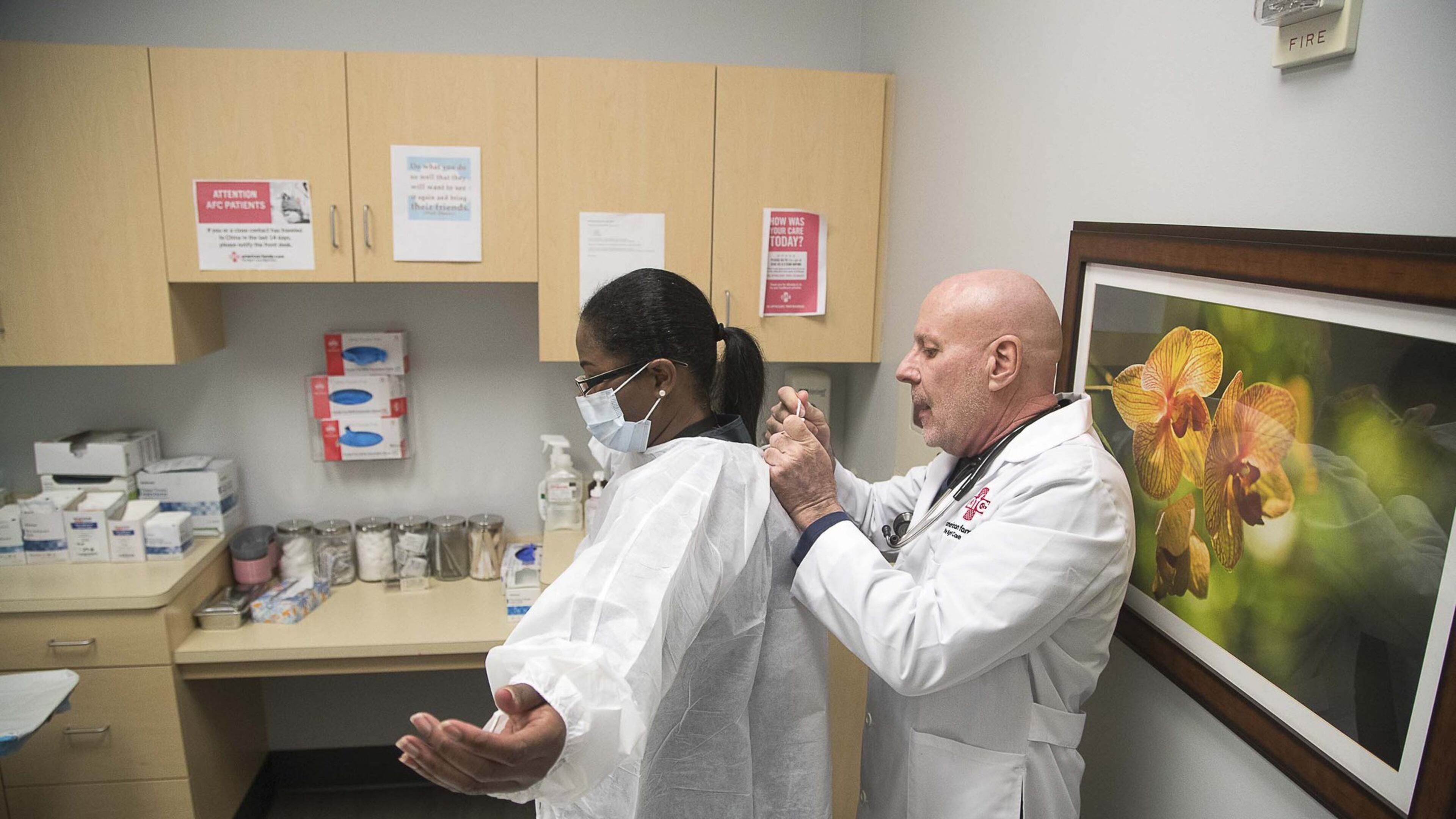 Dr. John Destito, at right, places a protective covering on office manager Kay Hayes at their American Family Care clinic in Buckhead. The two were going through a training for coronavirus procedures. Destito says their intake questionnaire is now screening all patients for factors like travel and coughing that could be indicators for coronavirus. (PHOTO by ALYSSA POINTER/ALYSSA.POINTER@AJC.COM)