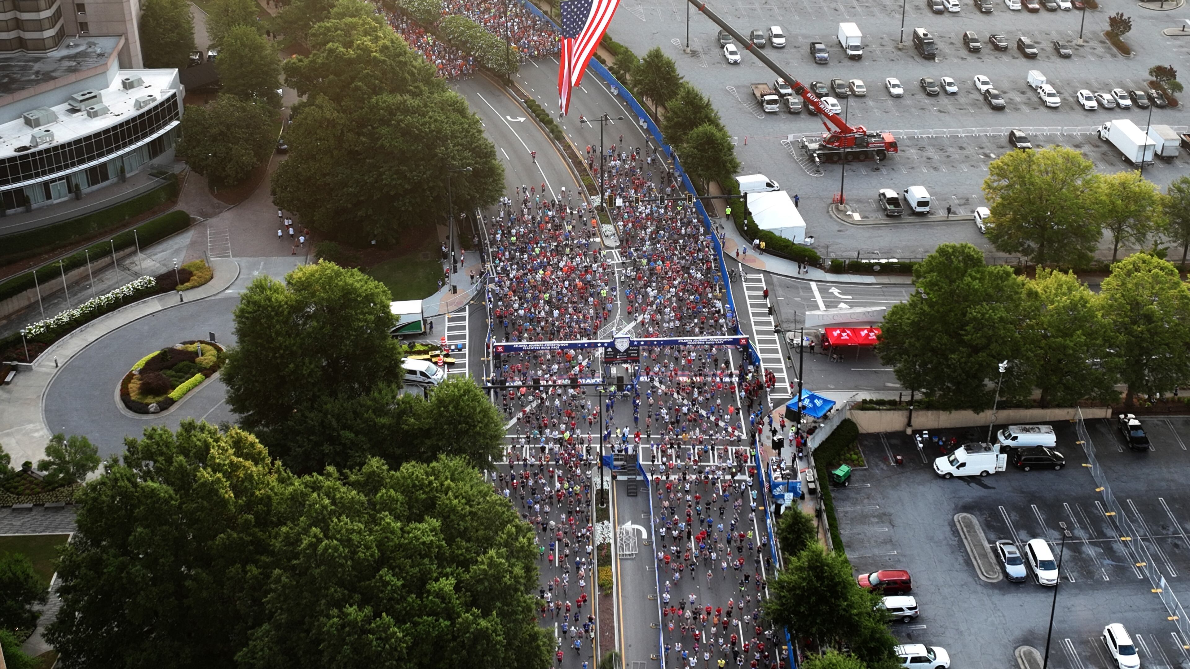 July 4, 2022 Atlanta - Aerial view shows runners cross the starting line of the 53rd Atlanta Journal Constitution Peachtree Road Race near Lenox Square Mall in Atlanta on Monday, July 4, 2022. (Hyosub Shin / Hyosub.Shin@ajc.com)