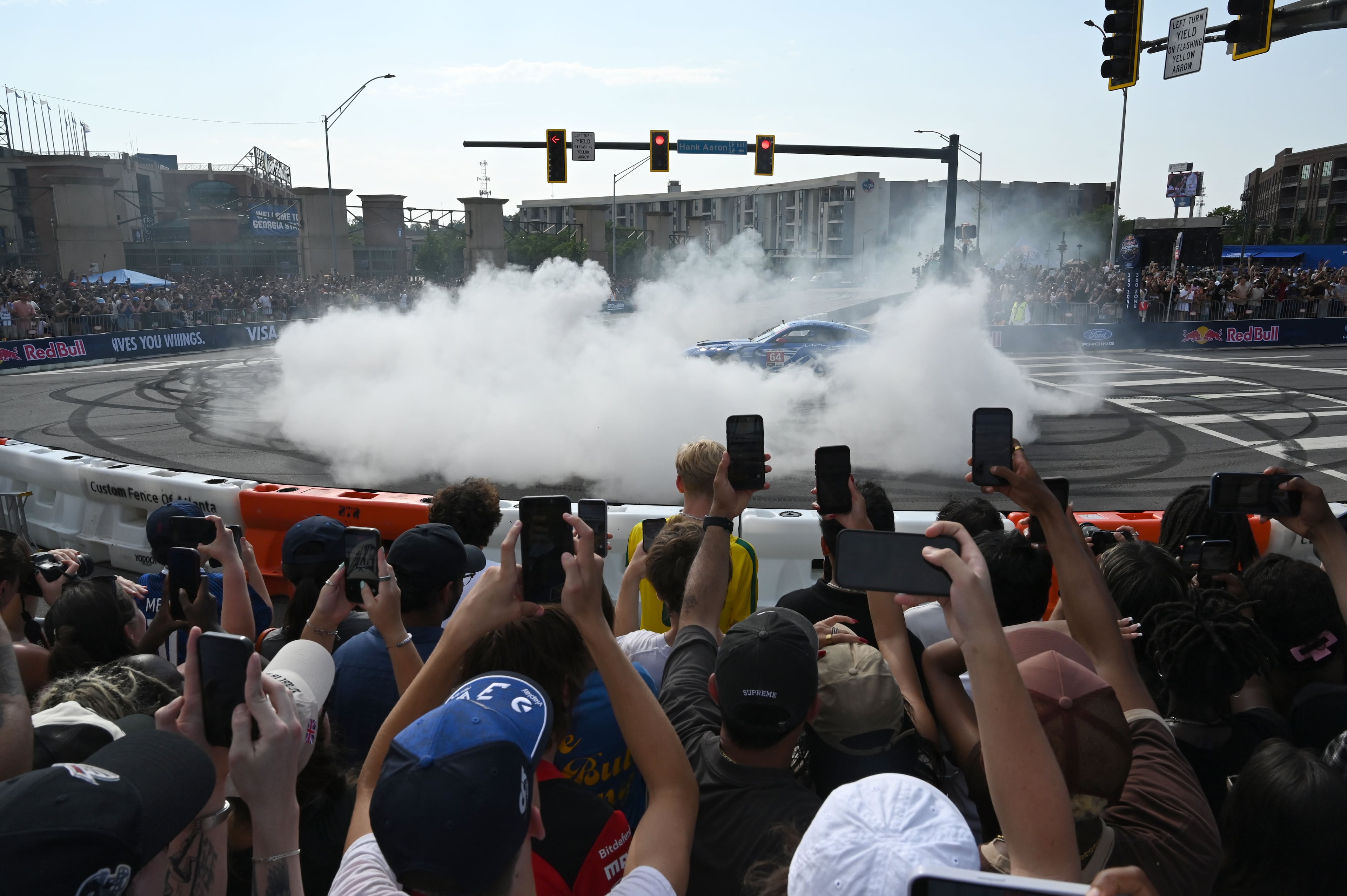 Spectators stand on chairs to watch a demonstration run on Hank Aaron Drive during the Red Bull Showrun Atlanta Presented by Ford Racing on Saturday, Aug. 1, 2026, in Atlanta. Atlanta city officials this week approved permits for the Red Bull Showrun that will allow the live motorsports demonstration event to go on as advertised along a roughly half-mile stretch of Hank Aaron Drive — a backup location after earlier plans to hold the event near Piedmont Park ran into opposition from Midtown residents. (Hyosub Shin/AJC)