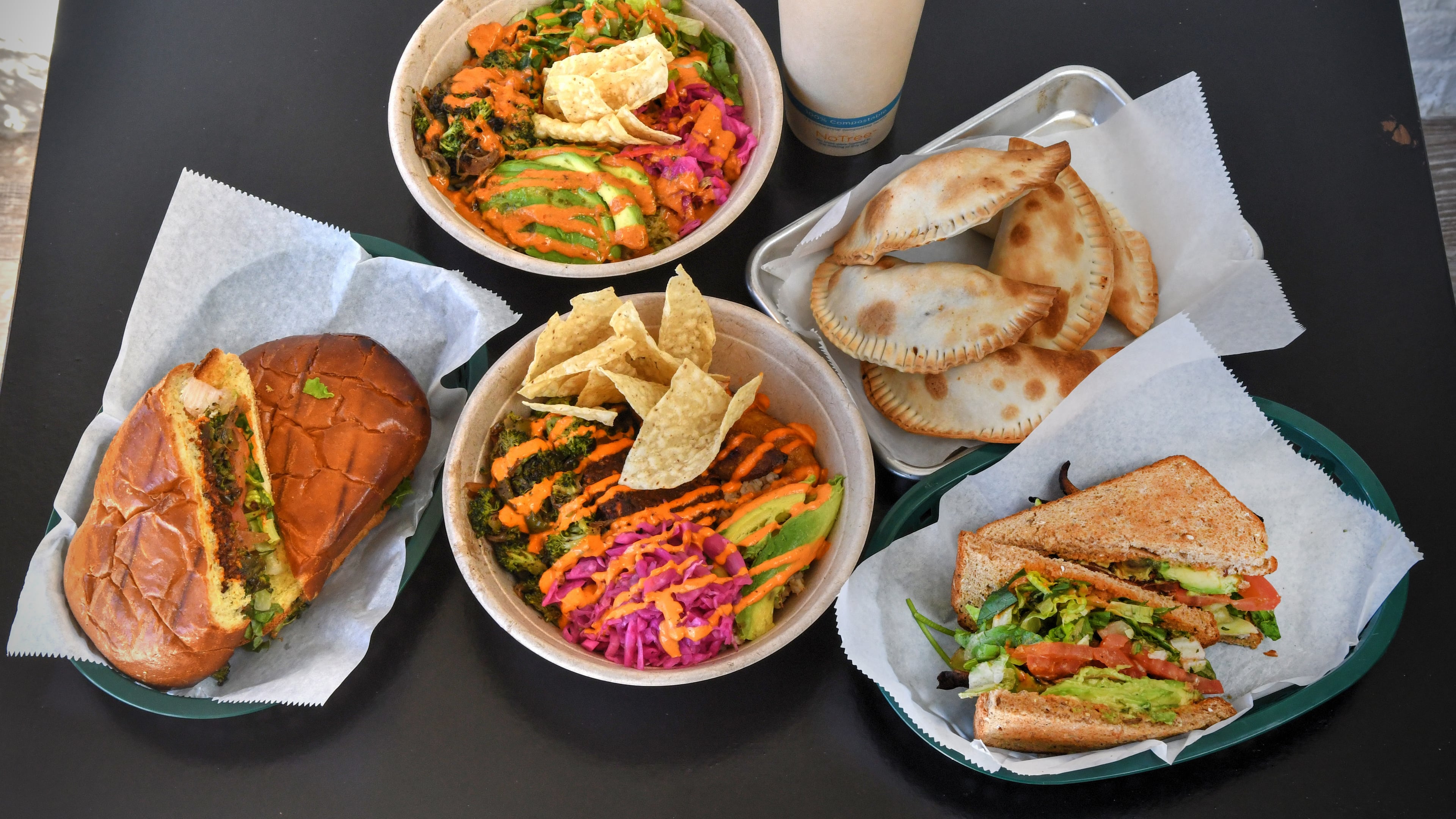 211026 Tucker, Ga: Top row from left: Lime to Me, Ginger Mango Pineapple (20 oz juice), Corn and Potato Empanada. From bottom row left: Chorizo Torta sandwich, Papi's Bowl, MBLTA sandwich. First Look at Papi Ali's, 2323 Main Street, Suite A1, Tucker, Ga. For 110221firstlook. (Chris Hunt for The Atlanta Journal-Constitution)
