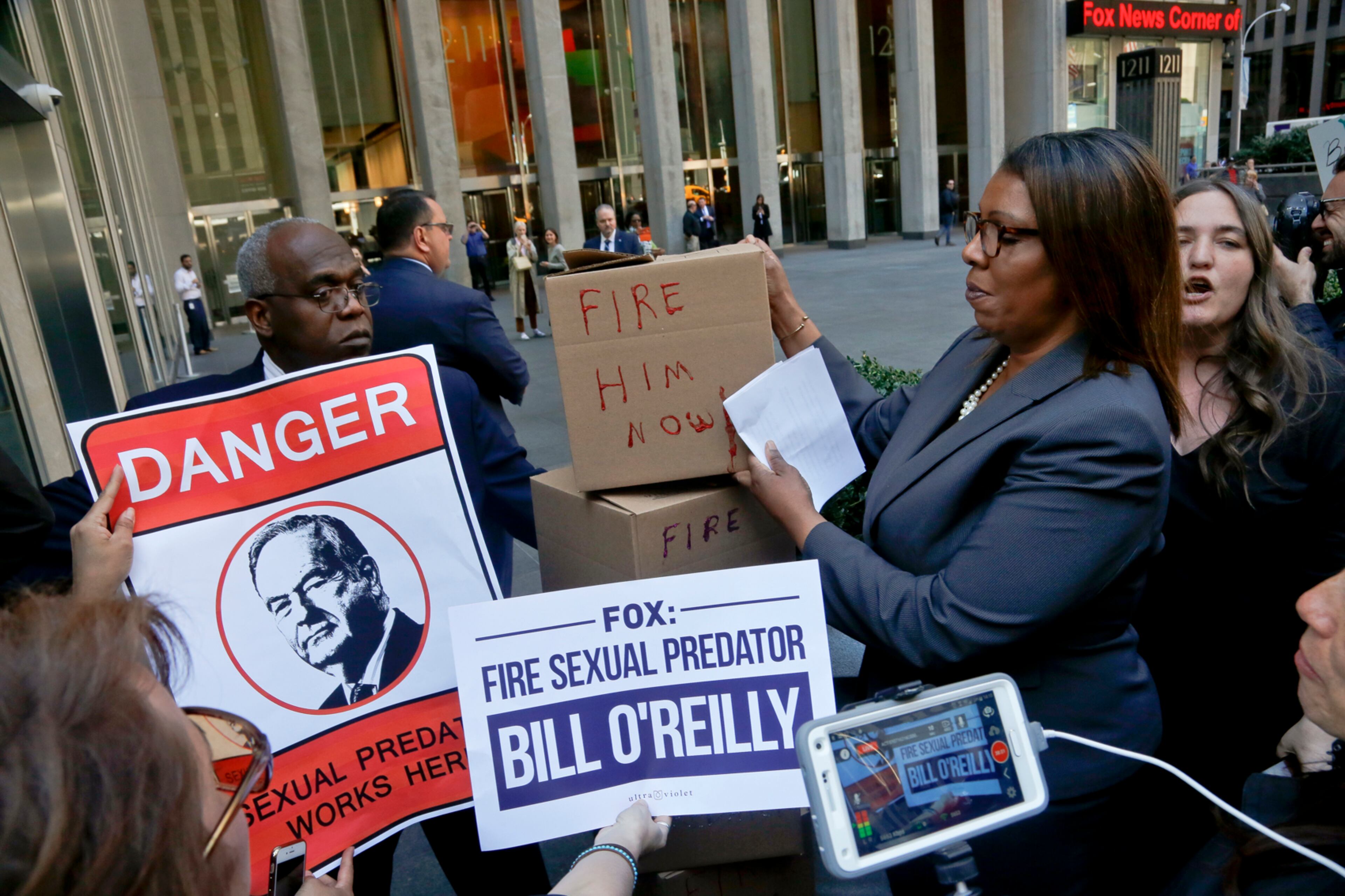A security guard blocks an entry way as New York Public Advocate Letitia James, second from right, and protestors attempt to deliver boxes of petitions during a rally outside Fox News headquarters, calling for the network to fire Bill O'Reilly, Tuesday April 18, 2017, in New York. O'Reilly's show has seen an advertising boycott in the wake of a report about settlements paid to quiet harassment allegations against him. (AP Photo/Bebeto Matthews)