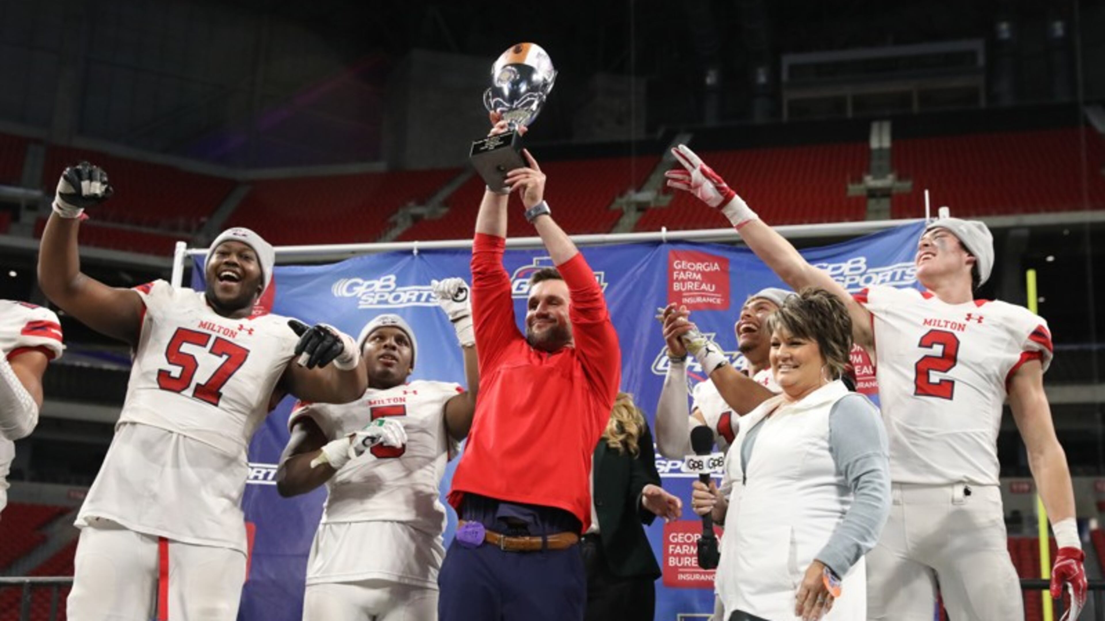 Milton coach Adam Clack celebrates with the trophy with players from left; Paul Tchio (57), Jordan Davis, Jordan Yates, and Dylan Leonard after their 14-13 win against Colquitt County in the Class AAAAAAA State Championship at Mercedes-Benz Stadium Wednesday, December 12, 2018, in Atlanta. Milton won 14-13. (JASON GETZ/SPECIAL TO THE AJC)
