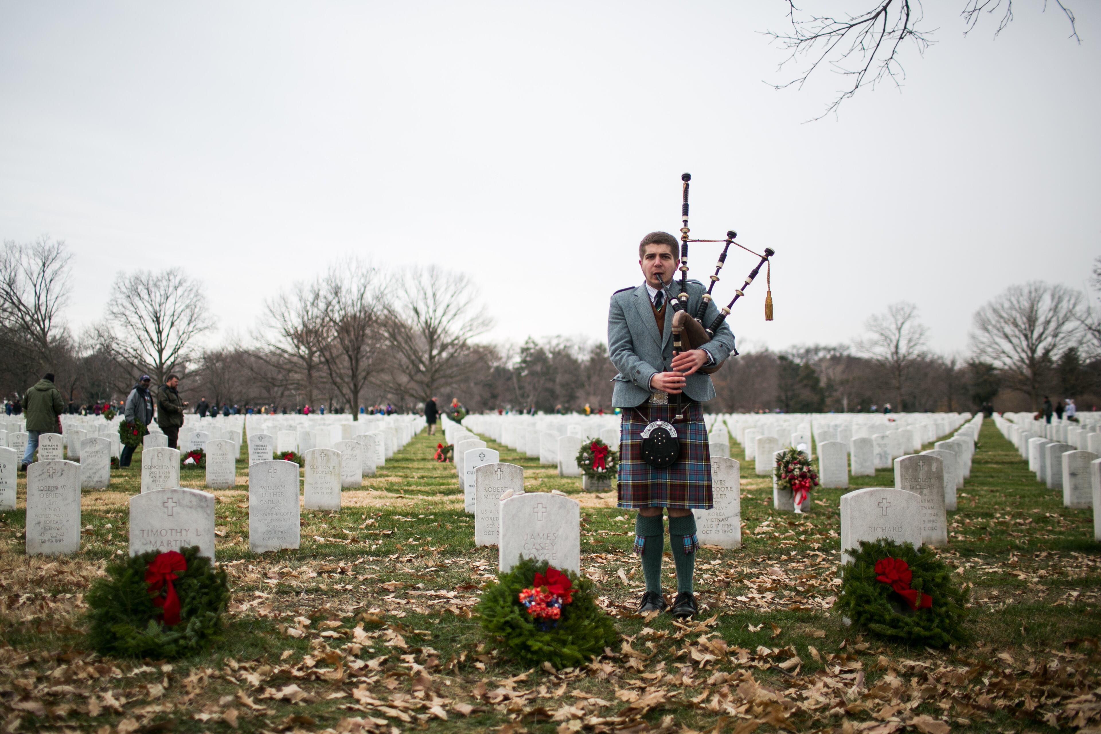 ARLINGTON, VA - DECEMBER 14: Sean Gearhart plays bagpipes at Arlington National Cemetery, December 14, 2013 in Arlington, Virginia. Volunteers and families of the fallen placed thousands of remembrance wreaths on headstones throughout the cemetery on National Wreaths Across America Day. (Photo by Drew Angerer/Getty Images)