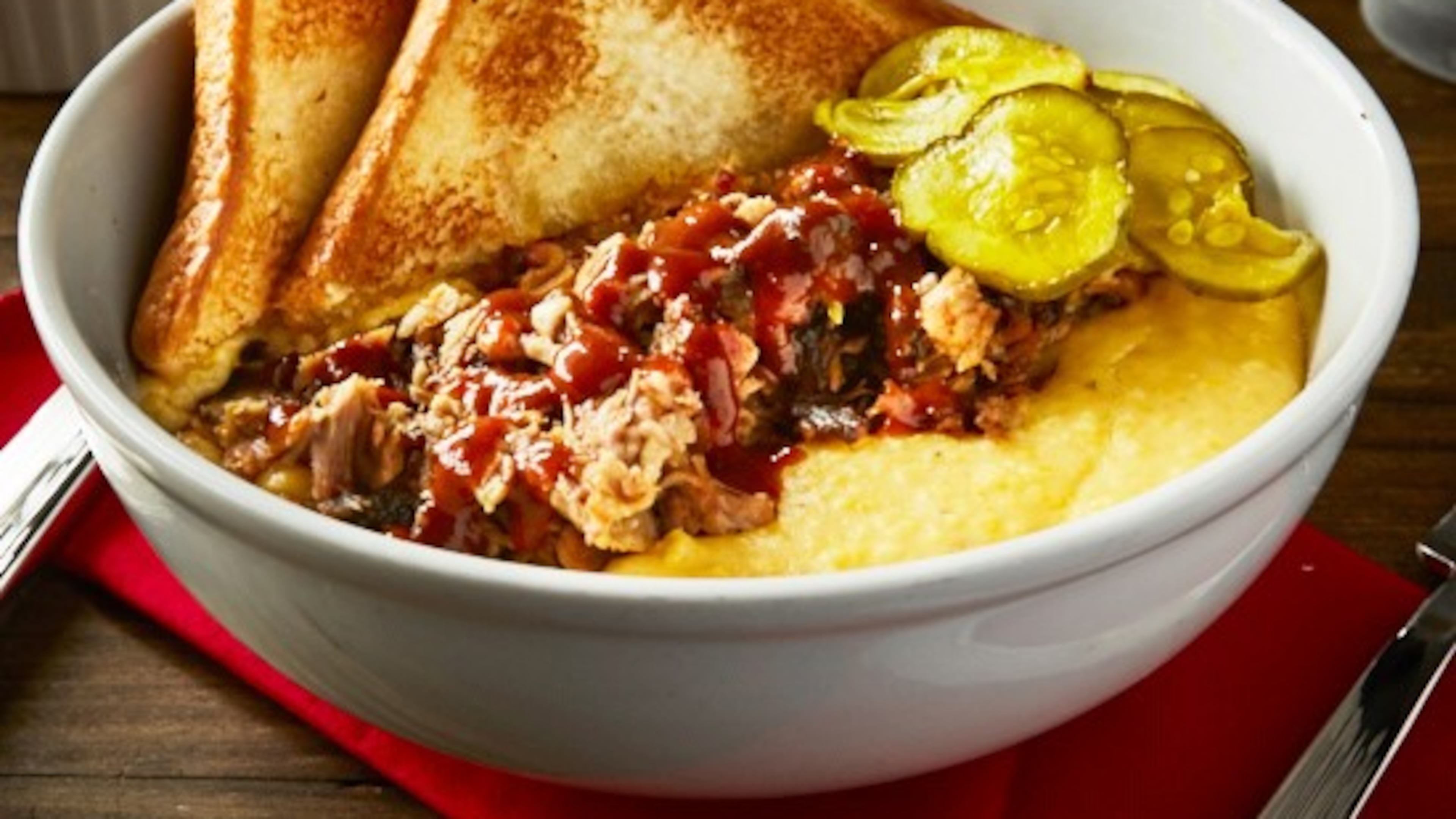 Savory pulled pork with stone ground cheddar grits, scallions, pickles, and house BBQ sauce from Sweet Auburn BBQ.