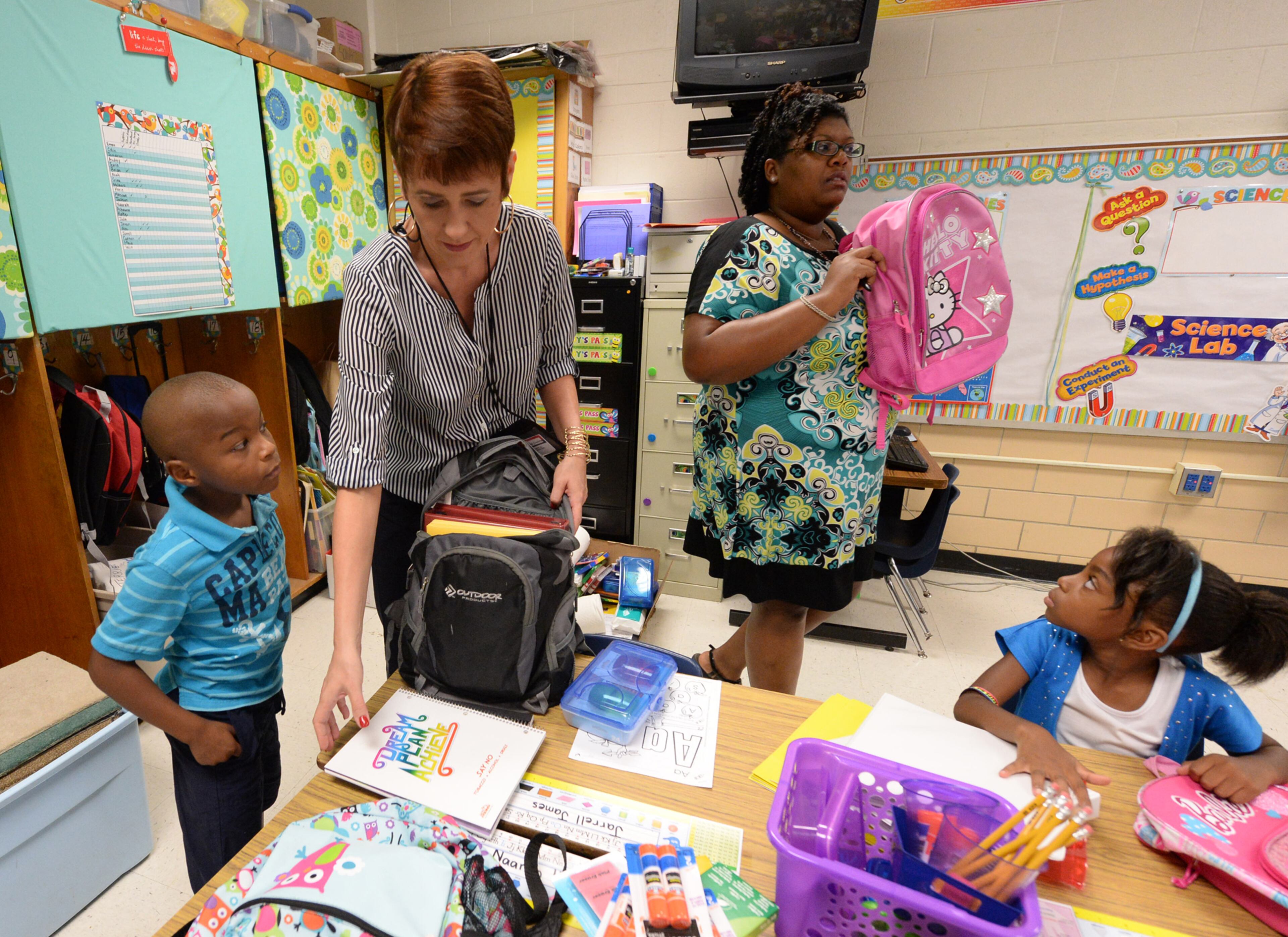 Colin Mott waits as paraprofessional Heather Sangster helps him go through his backpack as teacher Maegan Donnell gives instructions on the first day of school at Midvale Elementary on Monday, August 12, 2013. JOHNNY CRAWFORD / JCRAWFORD@AJC.COM