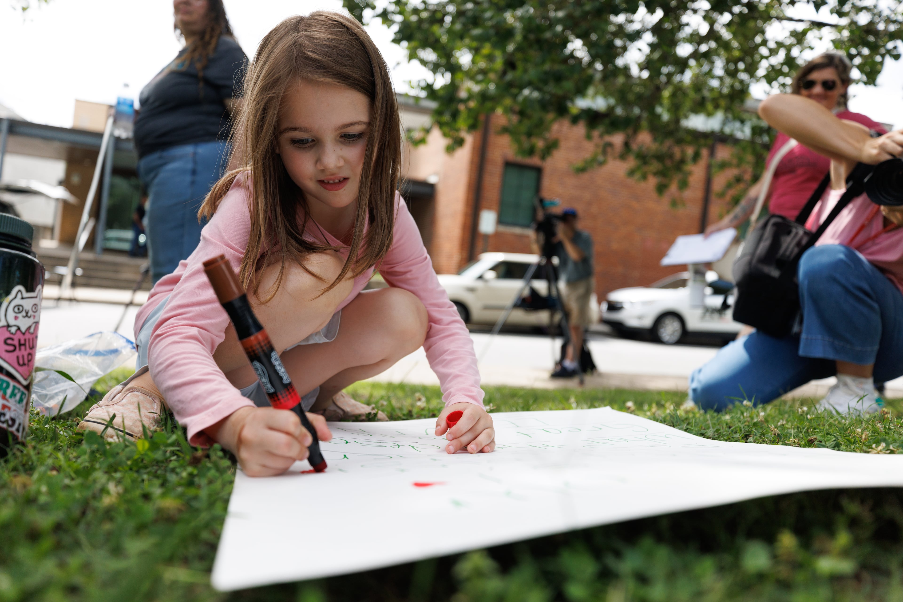 Magnolia Harrington, 5, draws hearts on a protestors' signs during a rally outside the Decatur school district’s central office on Thursday, May 28, 2026. (Estela Muñoz/AJC)