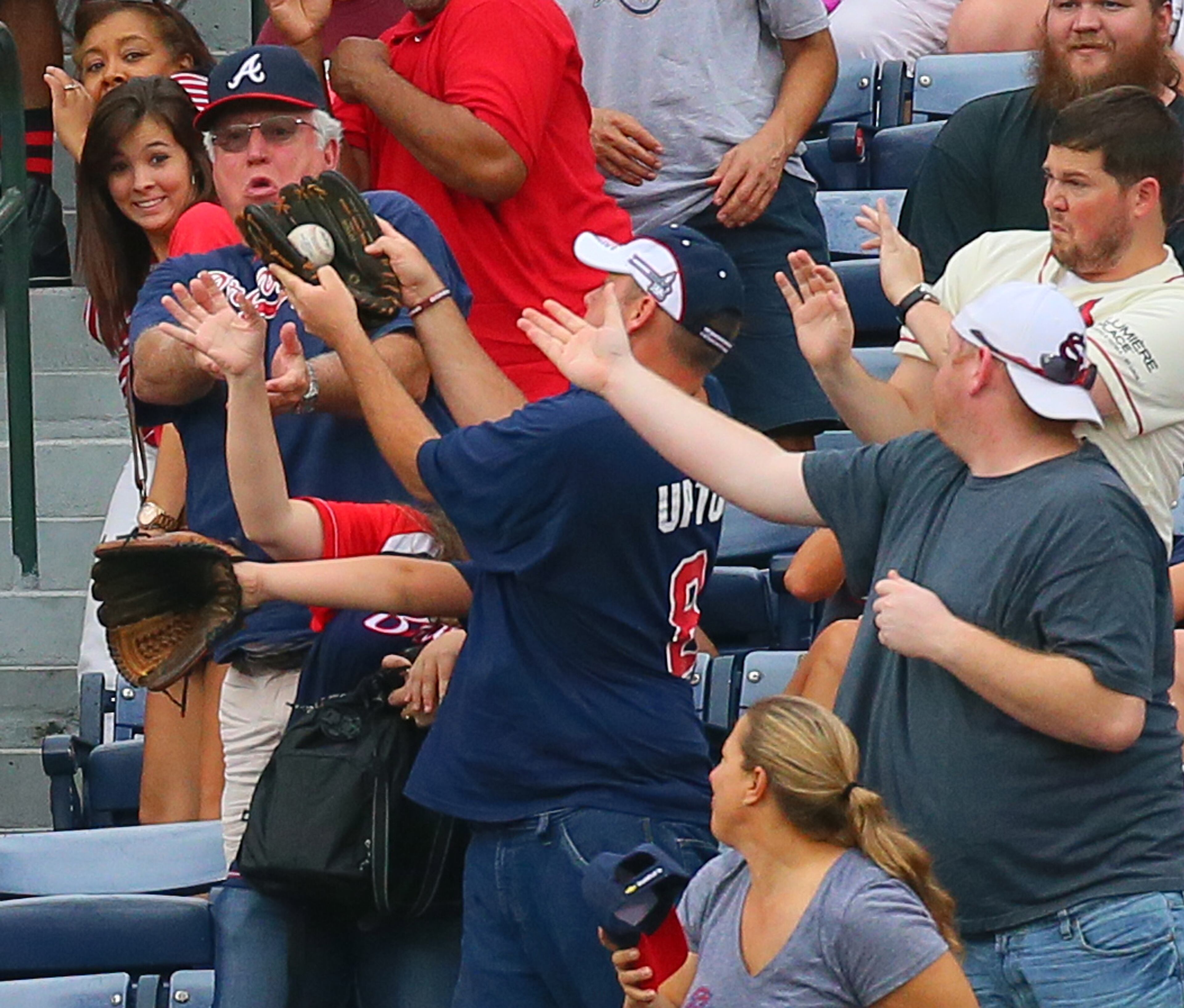 A Braves fan has an unorthodox way of using his glove to catch a solo homer by Marlins Jeff Mathis during the second inning of a MLB baseball game on Sunday, Sept. 1, 2013, in Atlanta.