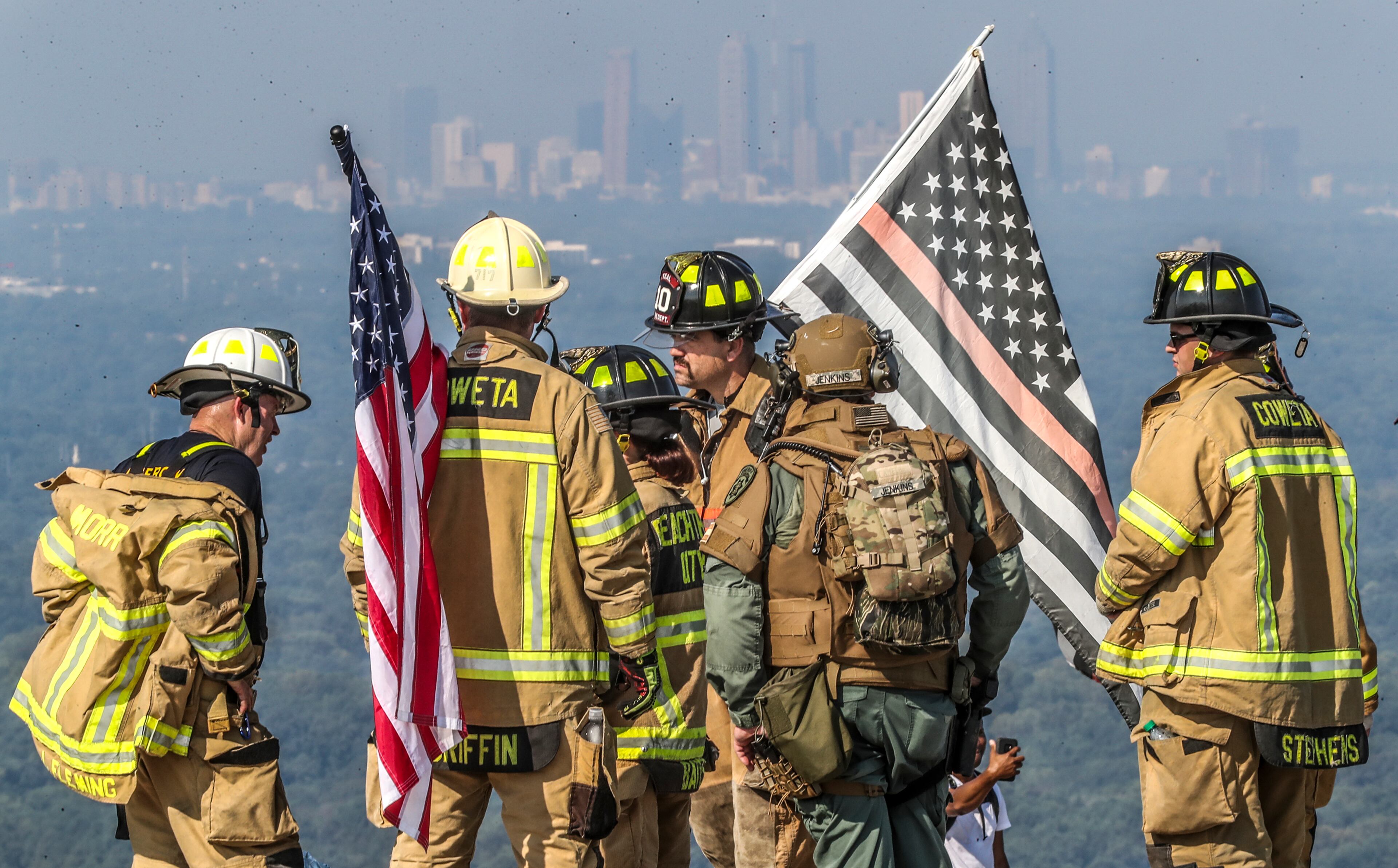 September 11, 2019 Stone Mountain: Union City firefighter, Andy Hinesley (center) gathers with Coweta County firefighters and sheriff deputy, Morrow and Peachtree City firefighters on top of the mountain after their climb to the top against the Atlanta skyline. About 100 firefighters ascended to the top of Stone Mountain on Wednesday morning, Sept. 11, 2019 in honor of the lives lost 18 years ago on 9/11. First responders from Fayetteville, Fayette County, Henry County, DeKalb County, Atlanta, Spalding County, Union City, Morrow and Barrow County took part in the fifth annual hike in full firefighting gear. The City of Fayetteville Fire Department sponsors the climb and founded it 5-years ago. The trek began after 9 a.m. The 1-mile climb is equivalent to walking up about 160 flights of stairs. Several observances were scheduled Wednesday around the metro area to honor the 3,000 people killed on September 11, 2001, in what is considered the largest loss of life resulting from a foreign attack on American soil. More than 300 firefighters and paramedics died responding to the terrorist attacks. JOHN SPINK/JSPINK@AJC.COM