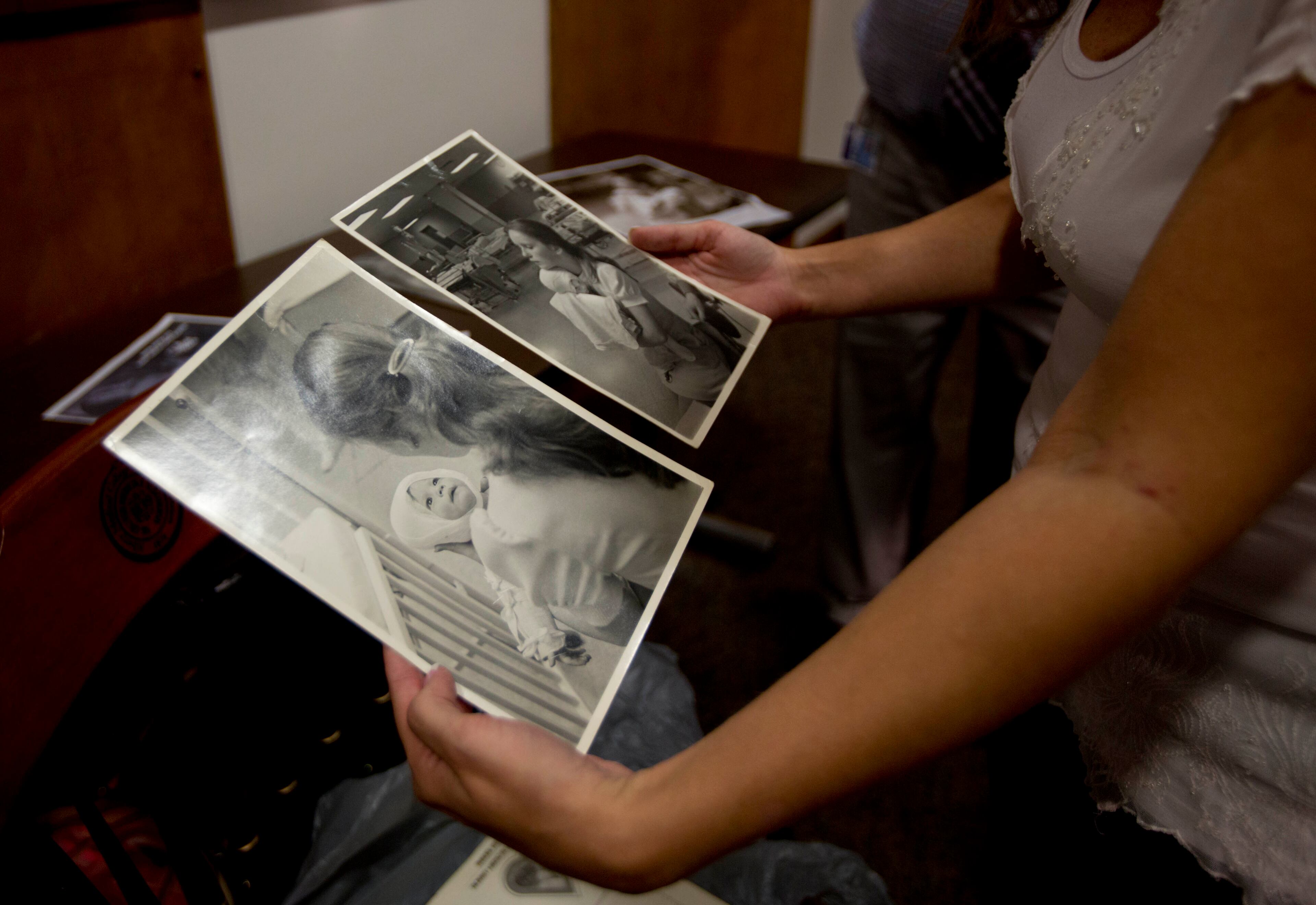 Amanda Scarpinati holds old photographs of herself being held by a nurse before a news conference at Albany Medical Center on Sept. 29, 2015, in Albany, N.Y. The upstate New York woman who suffered severe burns as an infant is finally getting the chance to thank the hospital nurse who cared for her, thanks to a social media posting that revealed the identity of the nurse in 38-year-old photos.