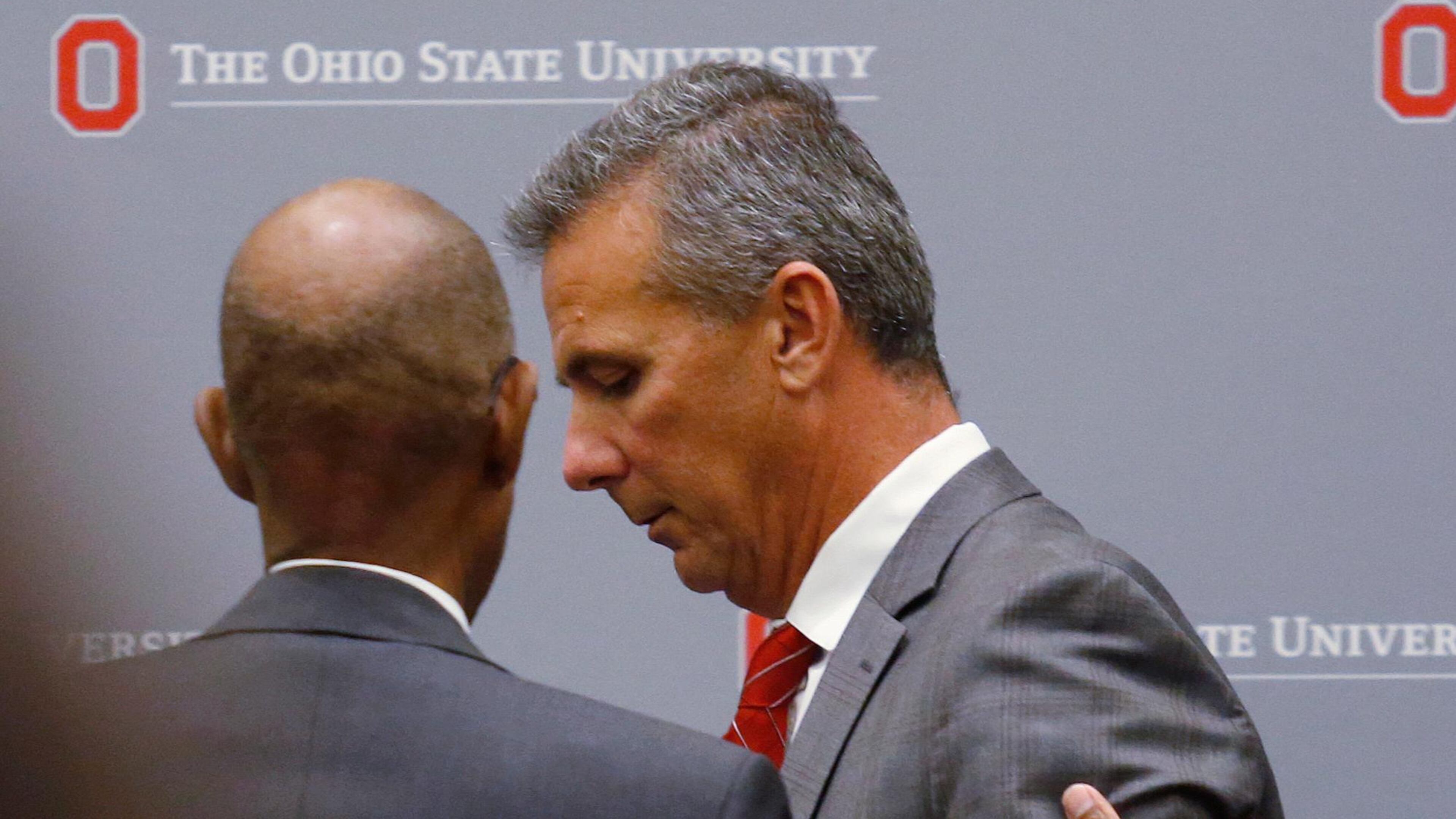 Ohio State University President Michael Drake offers words to football coach Urban Meyer, who leaves the stage following a news conference in Columbus, Ohio, Wednesday, Aug. 22, 2018. (AP Photo/Paul Vernon)
