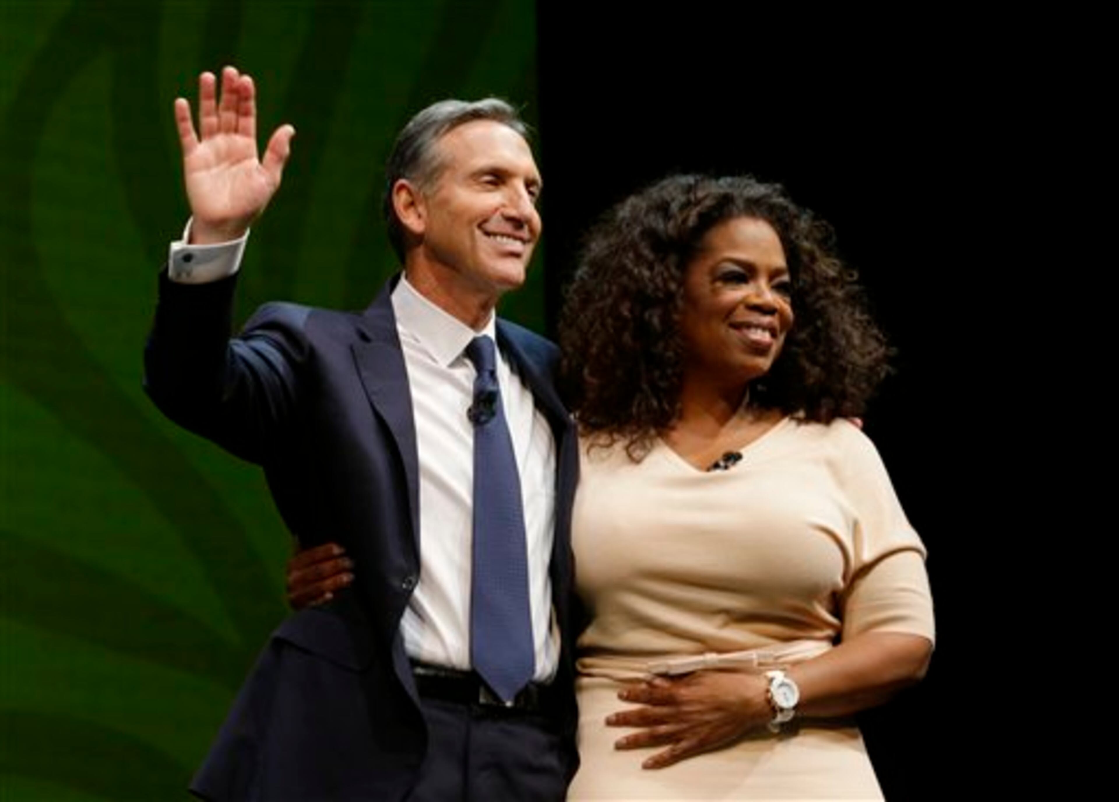 Howard Schultz, left, chairman and CEO of Starbucks Coffee Company, stands with Oprah Winfrey, right, after they announced their partnership to offer Teavana Oprah Chai tea, Wednesday, March 19, 2014, at Starbucks' annual shareholders meeting in Seattle. (AP Photo/Ted S. Warren)