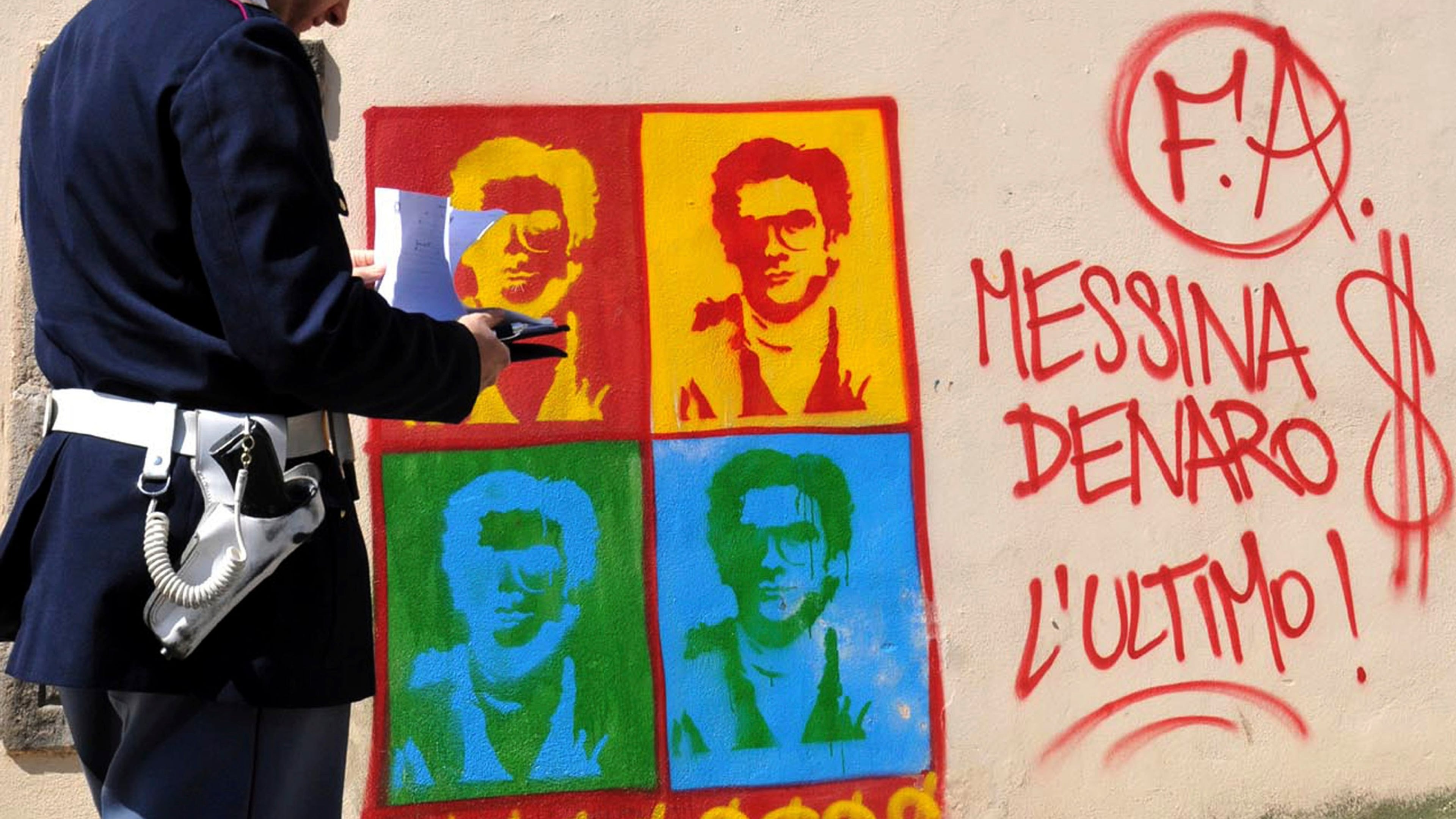 FILE - An Italian Police officer looks on at graffiti on the perimeter wall of Palermo's city's cathedral, portraying Matteo Messina Denaro, in Sicily, southern Italy, Thursday, April 24, 2008. (AP Photo/Alessandro Fucarini, File)