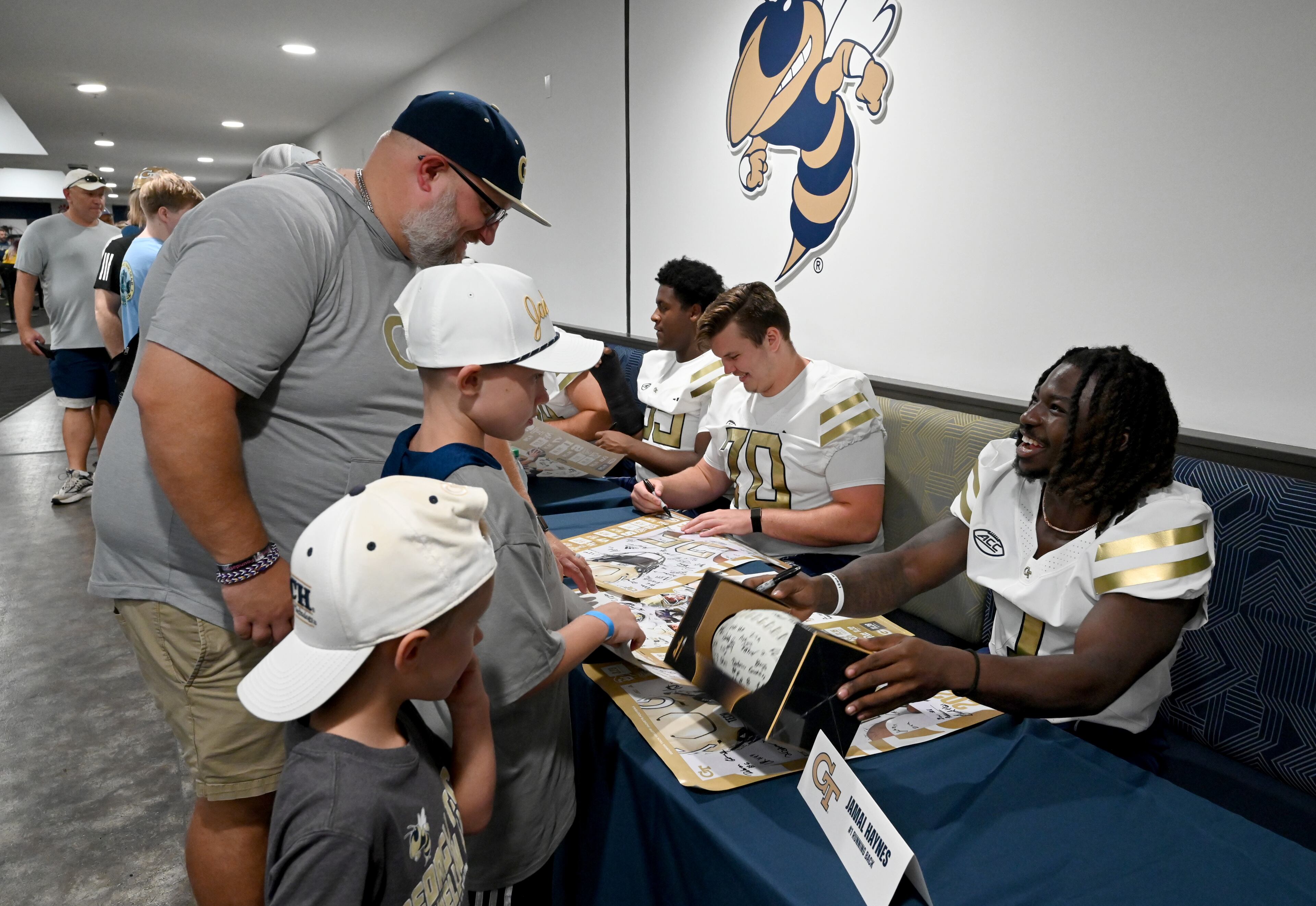 Georgia Tech running back Jamal Haynes (right) smiles as he and other players sign autographs for event attendees during the annual “First Saturday on The Flats” at Bobby Dodd Stadium, Saturday, August 2, 2025, in Atlanta. The Flats provides Tech fans with the opportunity to engage with their favorite Yellow Jackets ahead of the upcoming 2025 season. The event offers a variety of entertaining activities for the whole family, including a DJ, autograph opportunities, tailgate games and interactive experiences right on the field at Bobby Dodd Stadium. (Hyosub Shin / AJC)