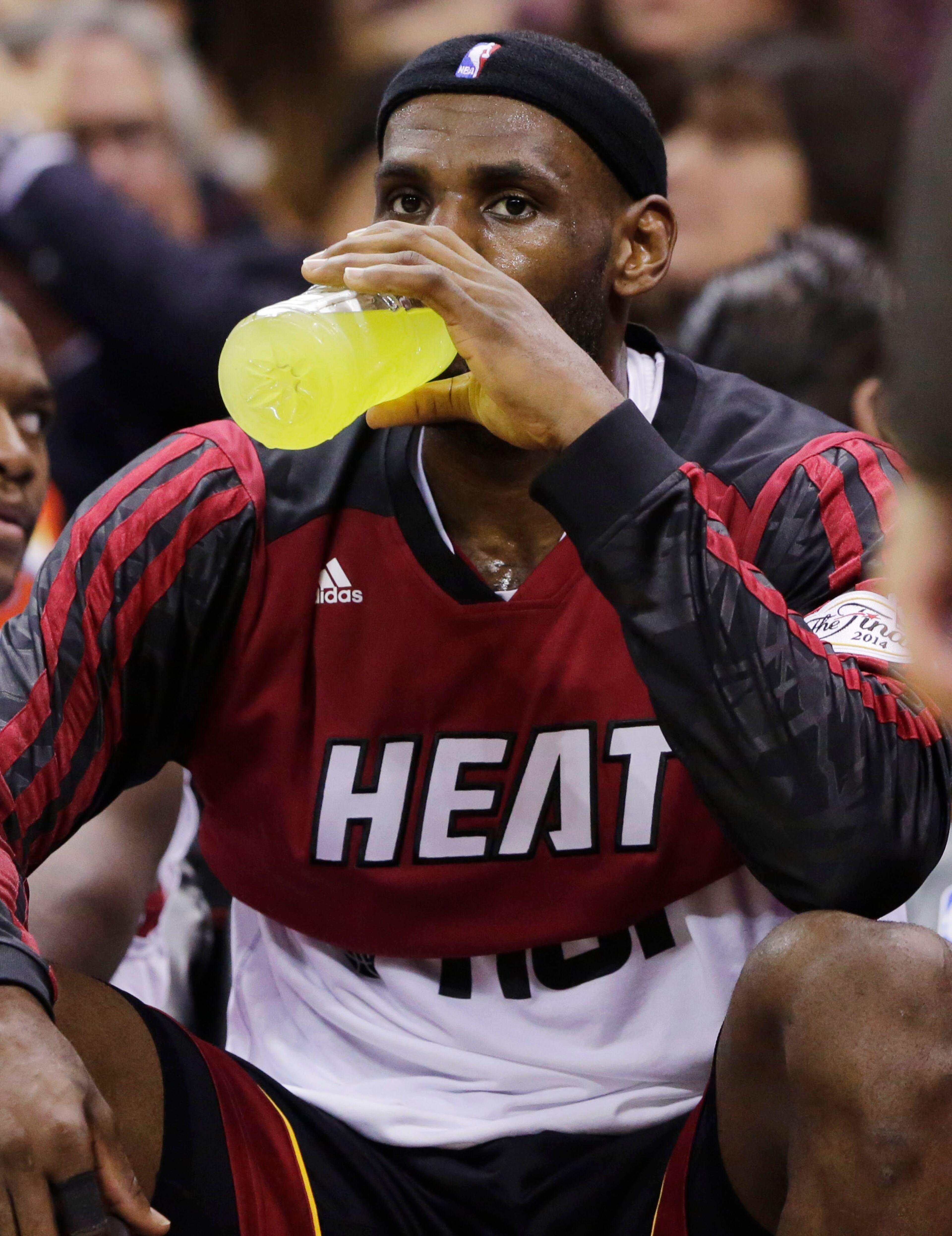 Miami Heat forward LeBron James has a sports drink while on the bench during the first half in Game 2 of the NBA basketball finals against the San Antonio Spurs on Sunday, June 8, 2014, in San Antonio. (AP Photo/Eric Gay)