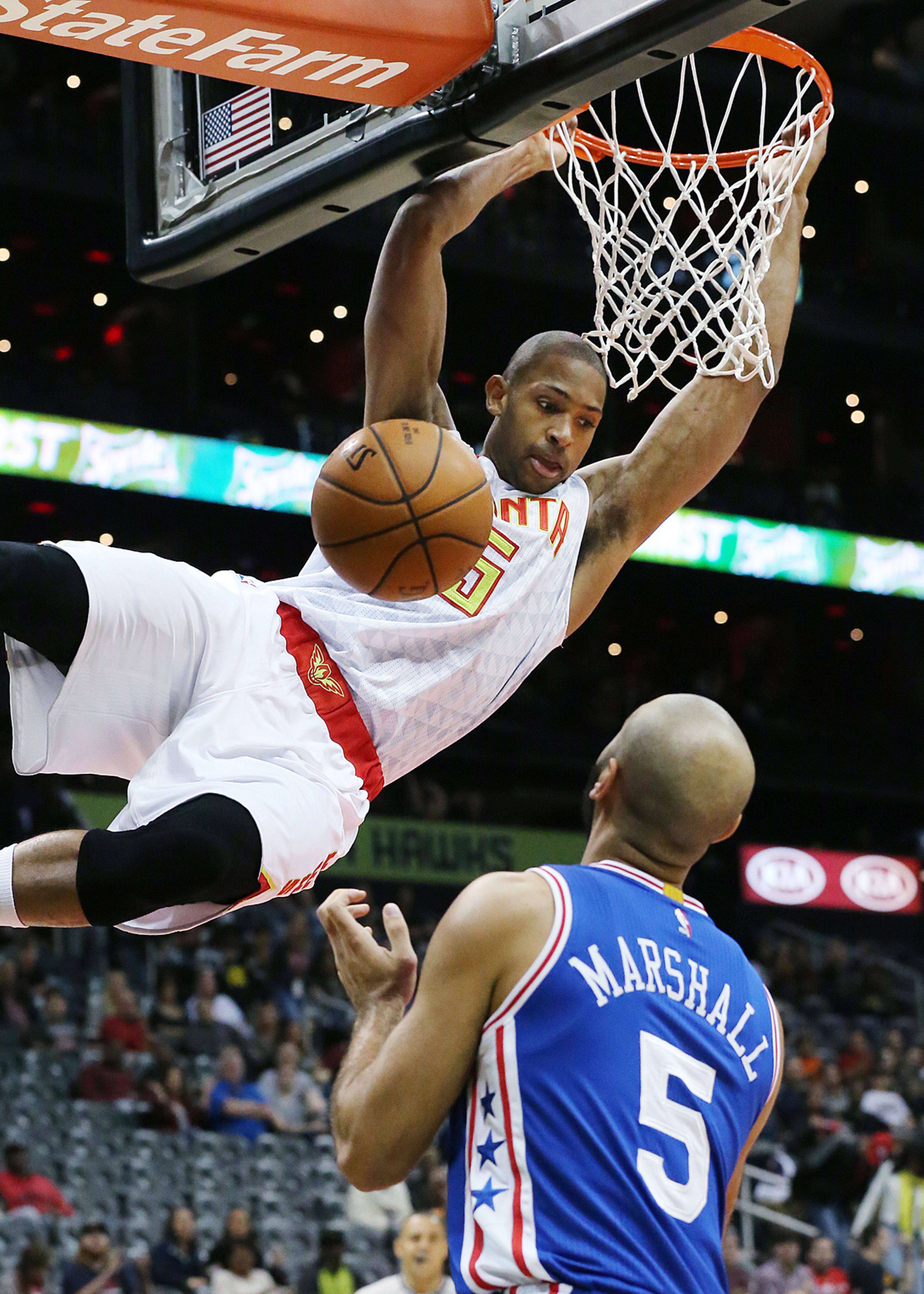 Hawks' Al Horford hangs on the basket after slamming in front of the 76ers' Kendall Marshall. Curtis Compton / ccompton@ajc.com
