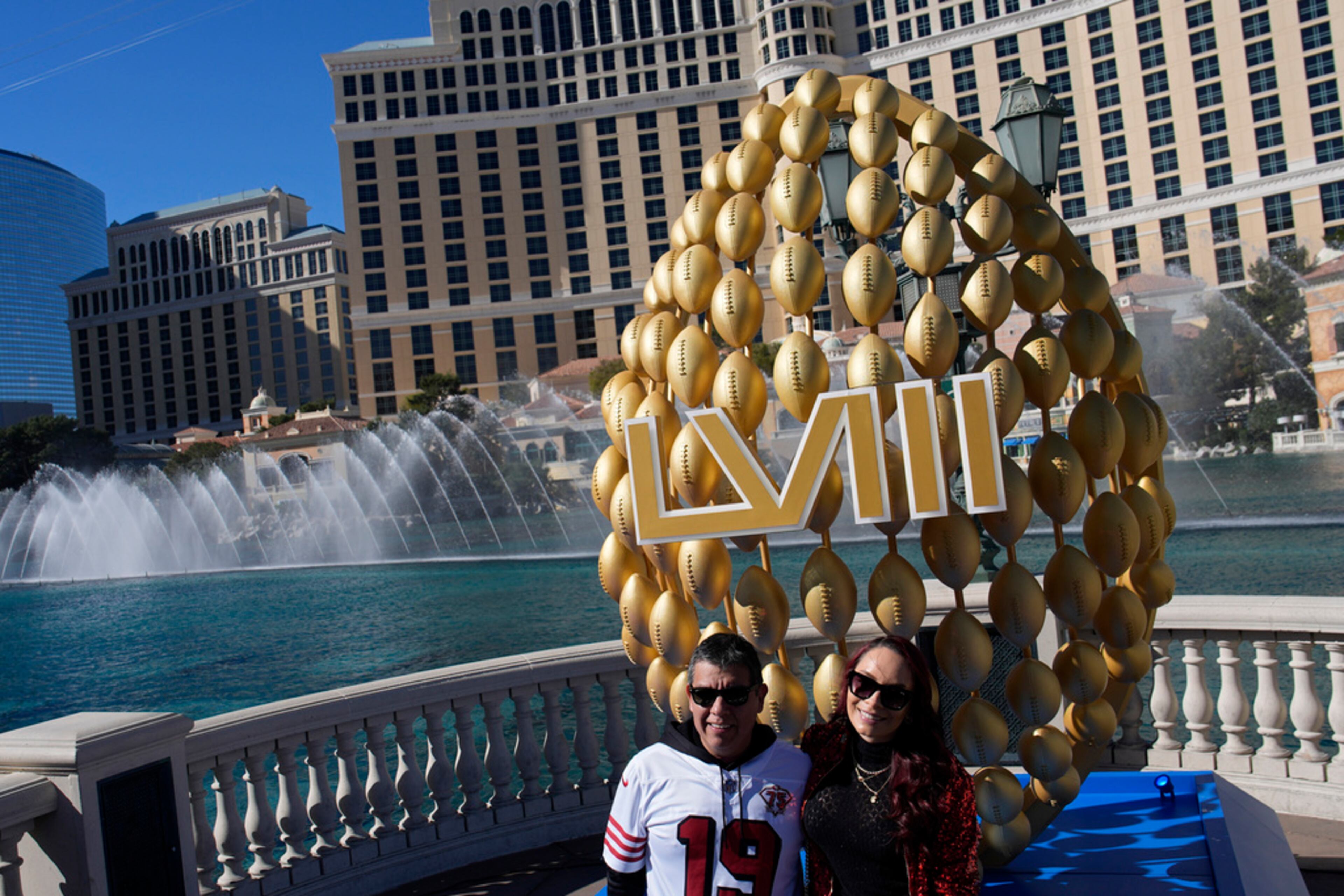 Fans pose by signage for the Super Bowl as the Bellagio fountains erupt along the Las Vegas Strip ahead of the Super Bowl 58 NFL football game Saturday, Feb. 10, 2024, in Las Vegas. The Kansas City Chiefs will play the the San Francisco 49ers Sunday. (AP Photo/John Locher)