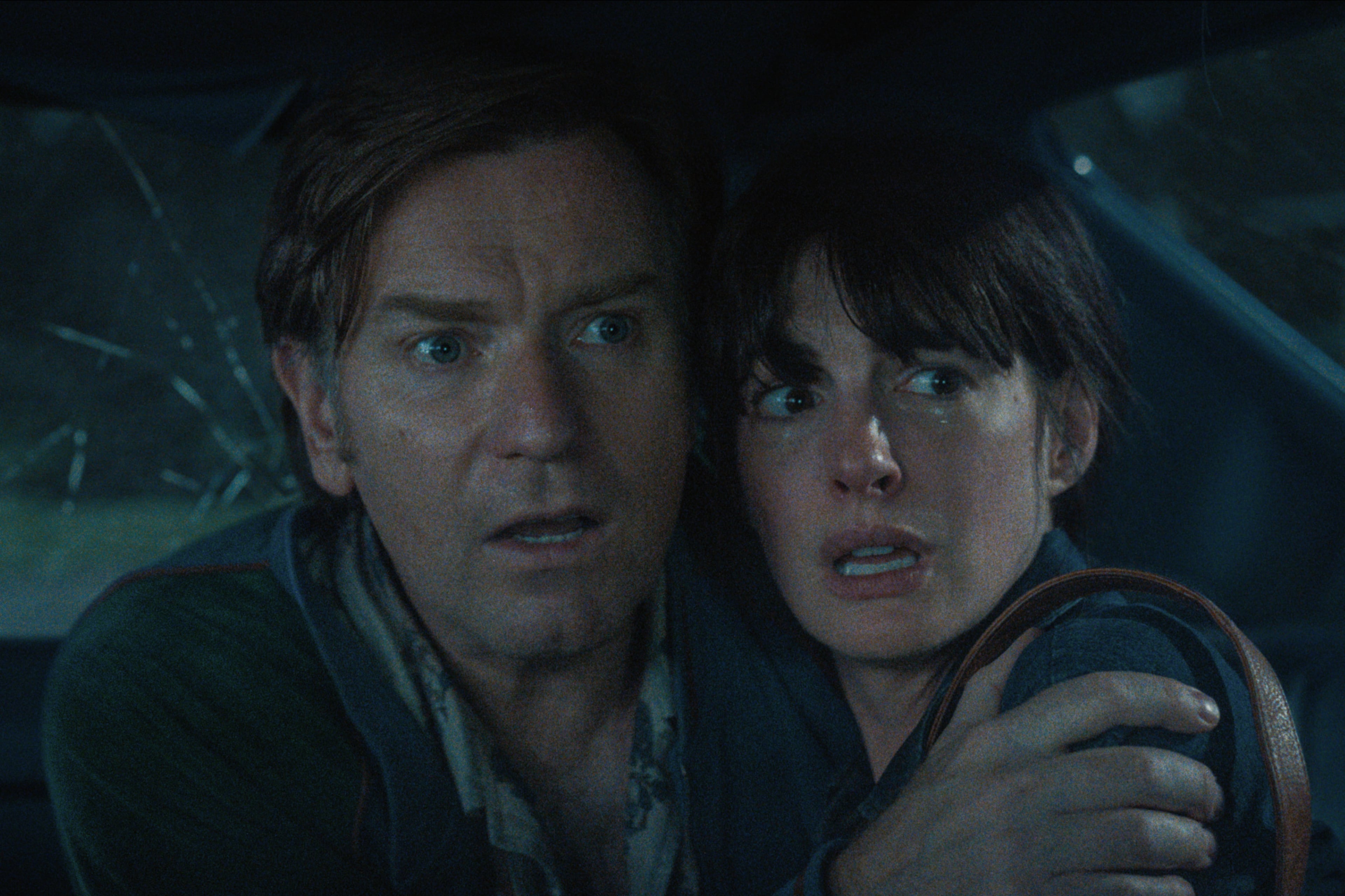 Ewan McGregor and Anne Hathaway inside a car trying to avoid a dinosaur in the sci-fi adventure "The End of Oak Street" shot in the Wisteria Gardens neighborhood of Southwest Atlanta in 2024. (Courtesy of Warner Brothers)