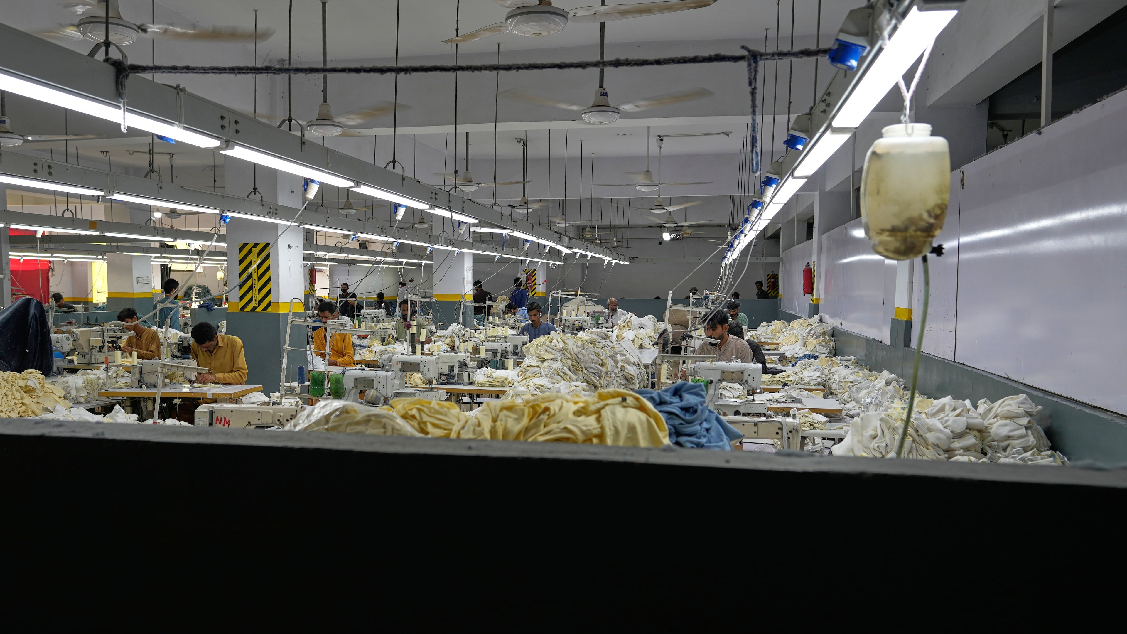 Workers stitch clothes at a factory with fans in Karachi, Pakistan, Friday, Oct. 2, 2026. (AP Photo/Anjum Naveed)