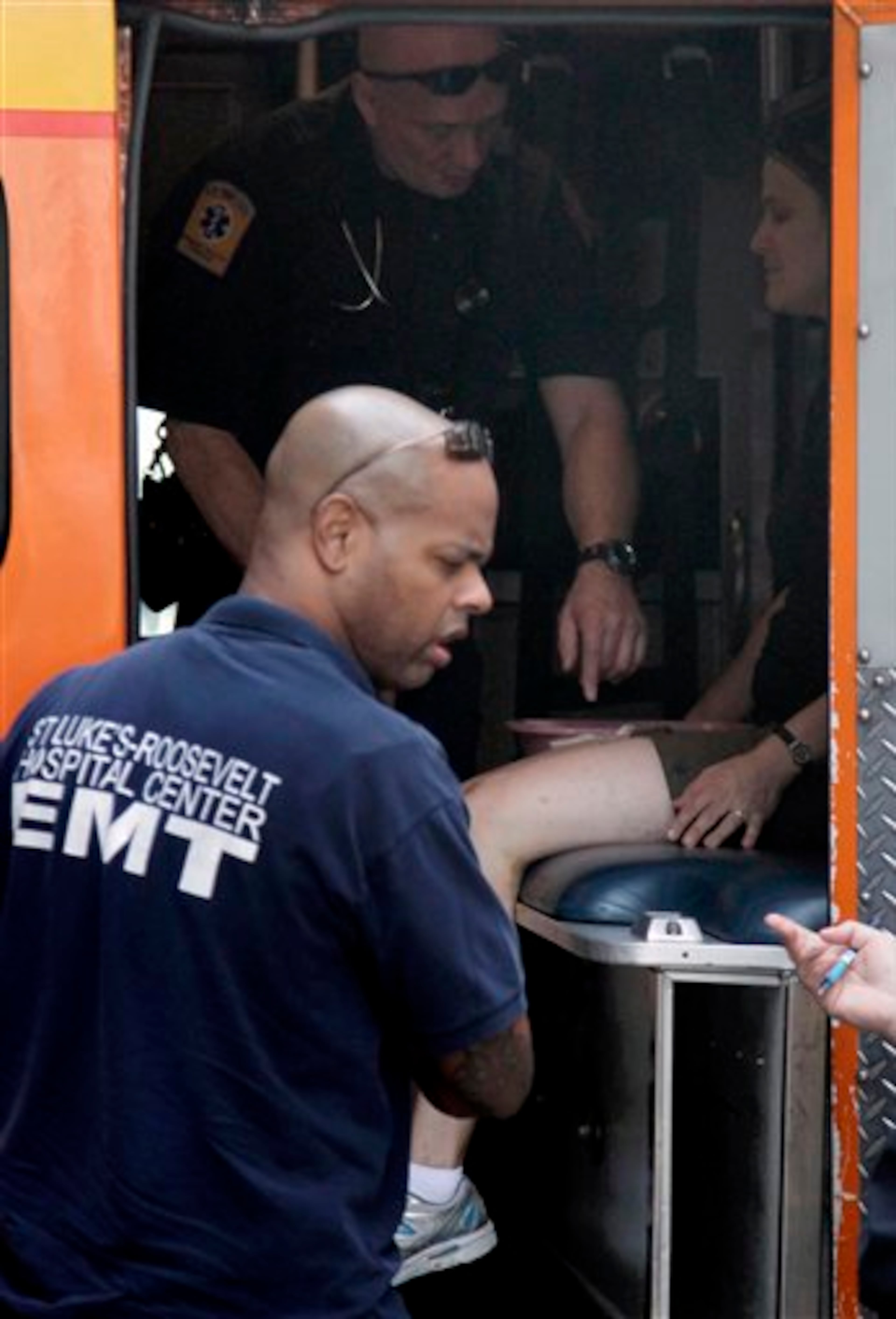 An unidentified woman is treated by emergency medical technicians inside an ambulance following a multiple shooting outside the Empire State Building, Friday, Aug. 24, 2012, in New York. At least four people were shot on Friday morning and the gunman was dead, New York City officials said. A witness said the gunman was firing indiscriminately. Police said as many as 10 people were injured, but it is unclear how many were hit by bullets. A law enforcement official said the shooting was related to a workplace dispute. The official spoke on condition of anonymity because the investigation was ongoing. (AP Photo/Mark Lennihan)