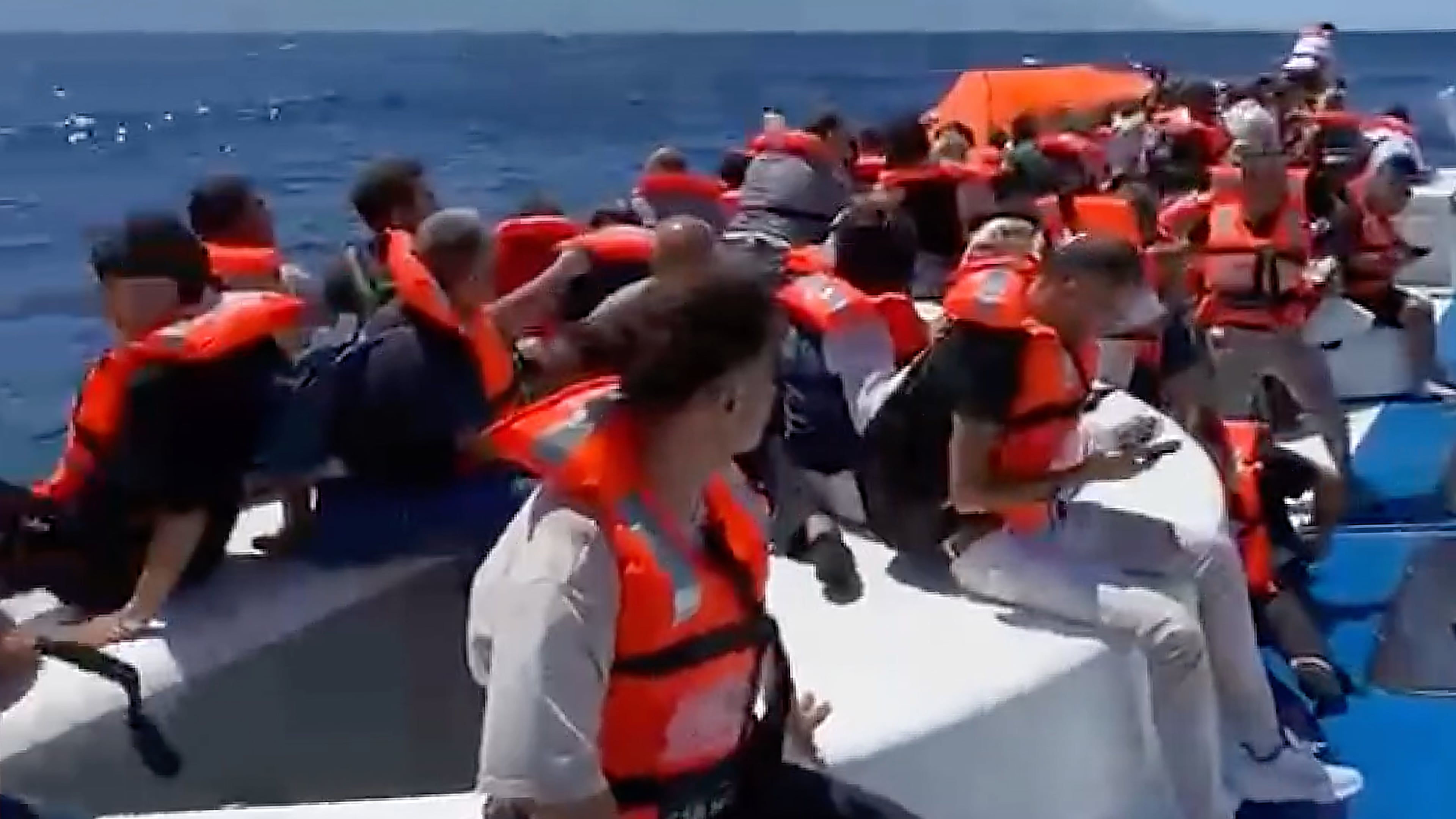 In this frame grab from a video, passengers wearing life jackets wait atop a capsized passenger vessel to be rescued off the coast of Girne, in the Turkish-occupied northern part of Cyprus, Sunday, Aug. 30, 2026. (DHA via AP)