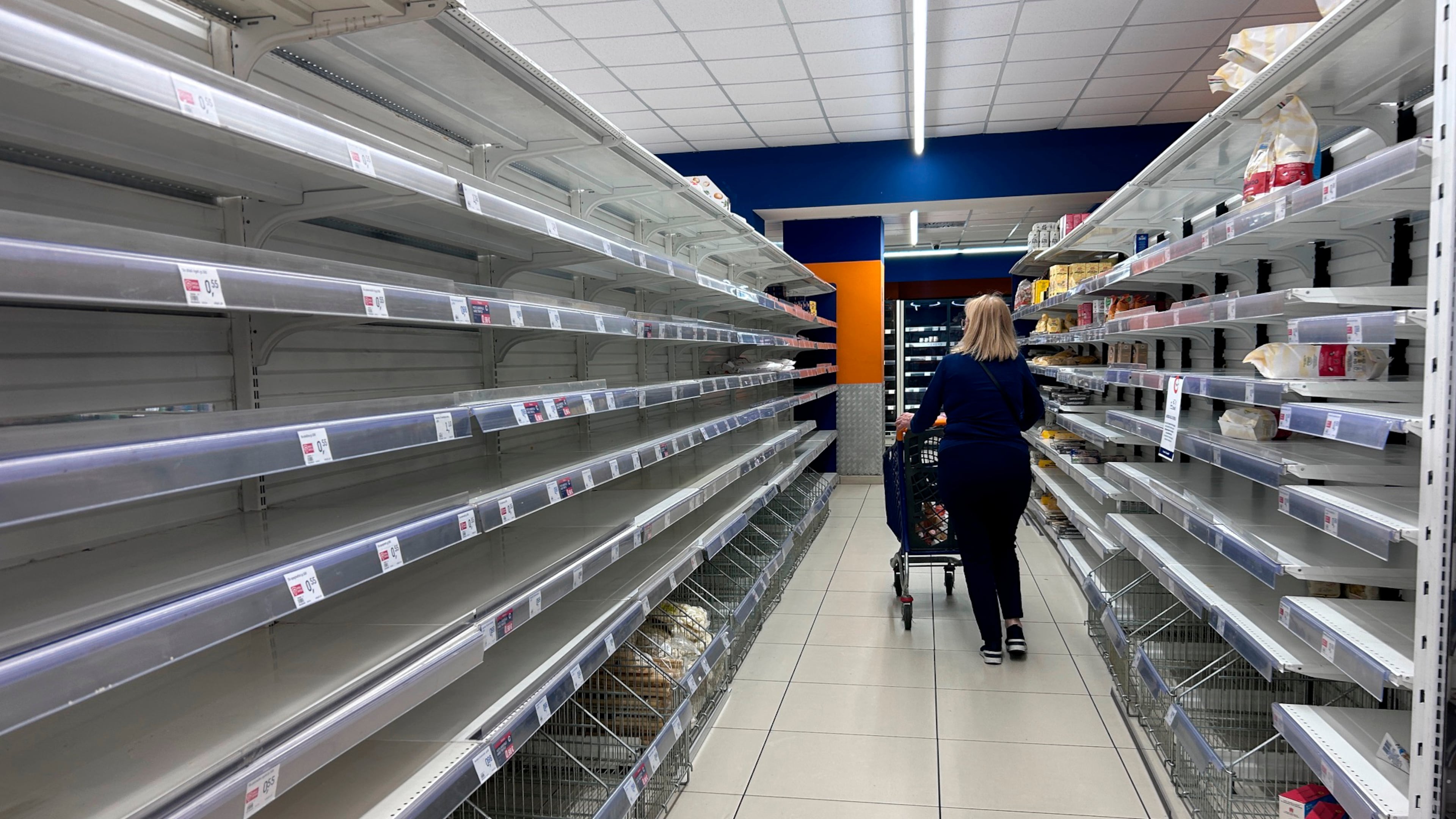 A woman walks past empty shelves at a supermarket in Naples, Italy, Tuesday, Oct. 20, 2026. (AP Photo/Alessandra Tarantino)