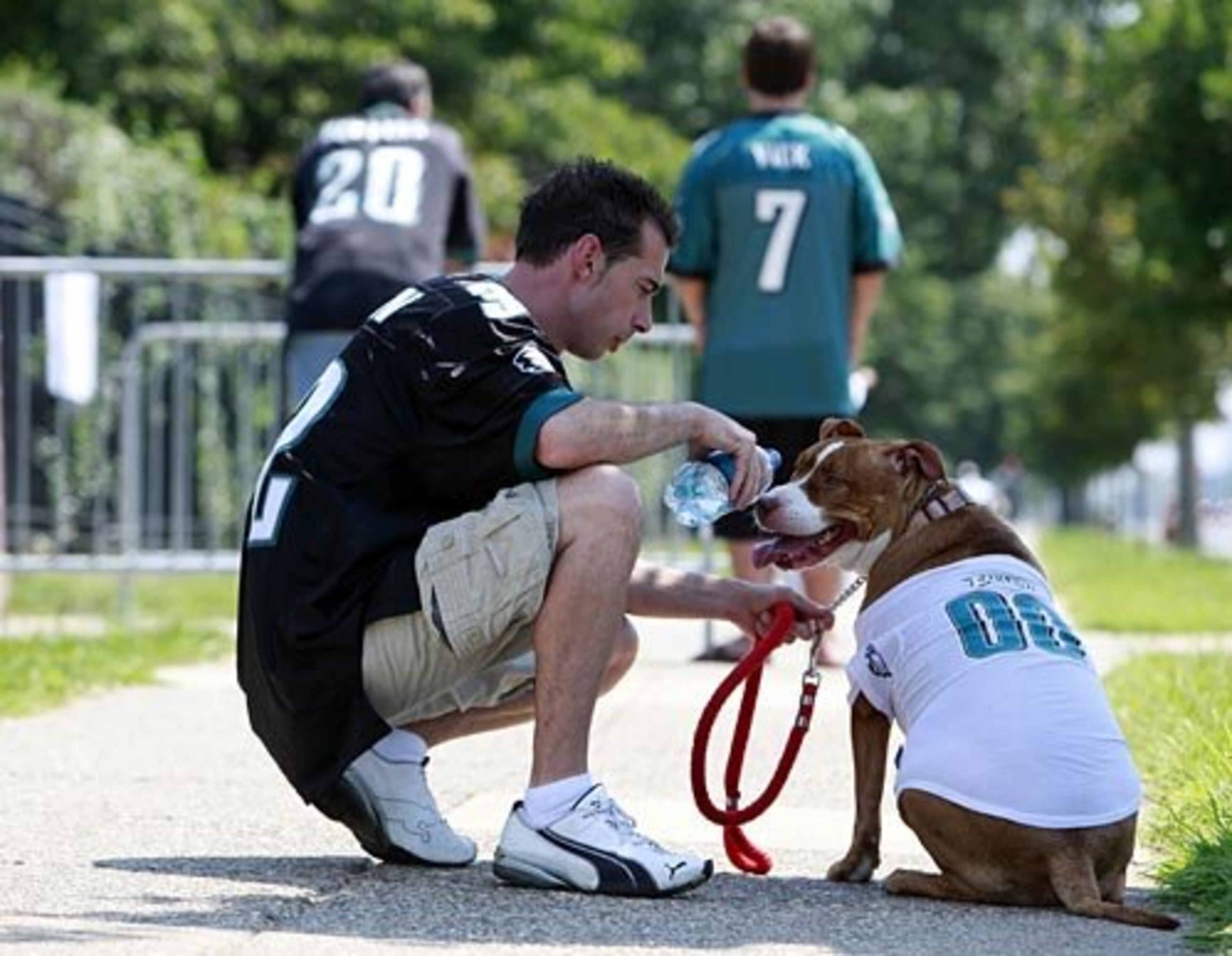 Eagles fan Frank Garren of West Milford N.J., with his dog Diva, takes a break outside the team's NFL football practice facility in Philadelphia Saturday, Aug. 15, 2009. Garren, who is a fan of pit bulls, is undecided on Michael Vick signing with the team.