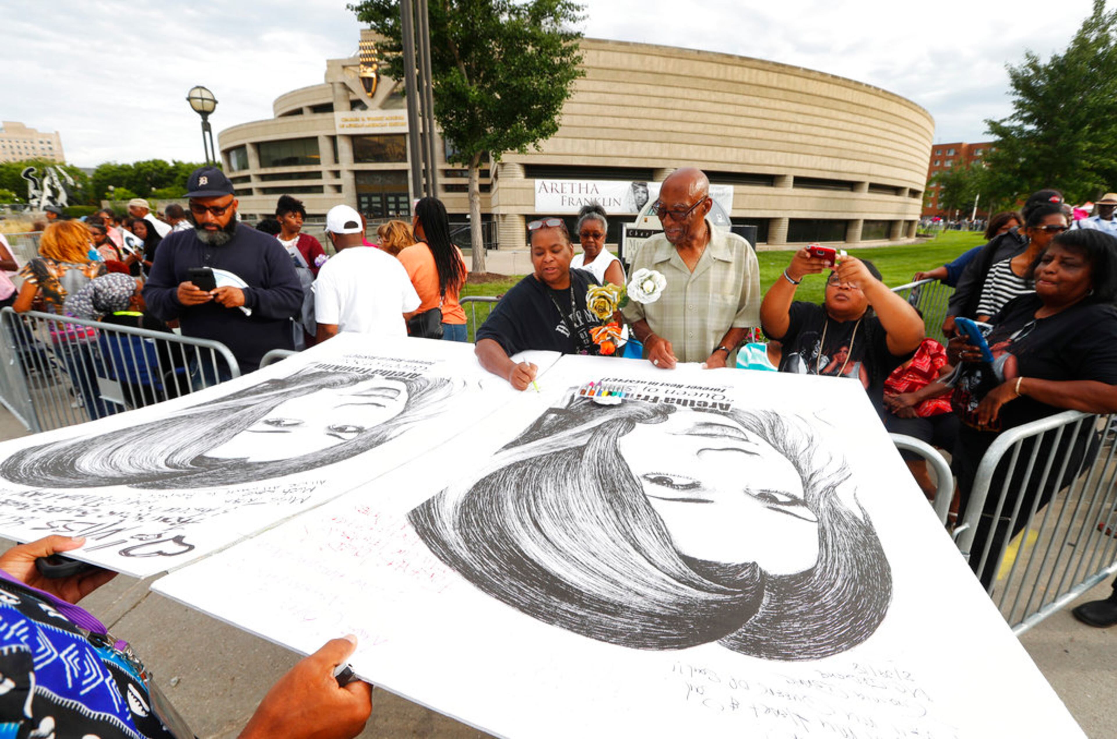 People in line sign well wishes on poster boards outside the Charles H. Wright Museum of African American History during a public visitation for Aretha Franklin in Detroit, Wednesday, Aug. 29, 2018. Franklin died Aug. 16, of pancreatic cancer at the age of 76. (AP Photo/Paul Sancya)