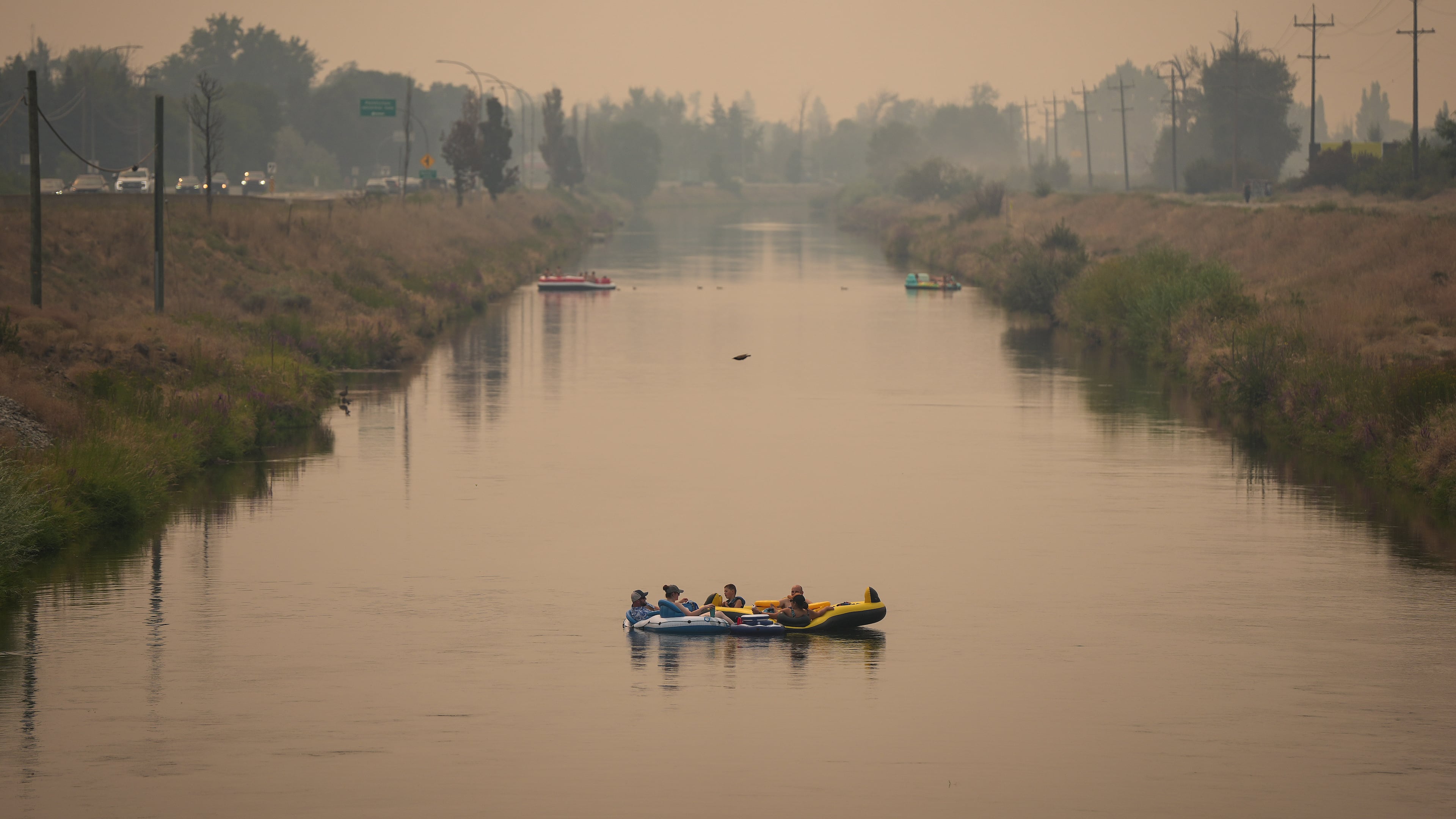 People float on the Channel Pathway that connects Okanagan Lake and Skaha Lake as smoke from wildfires burning in the region fills the air, in Penticton, British Columbia, Monday, Aug. 10, 2026. (Darryl Dyck/The Canadian Press via AP)