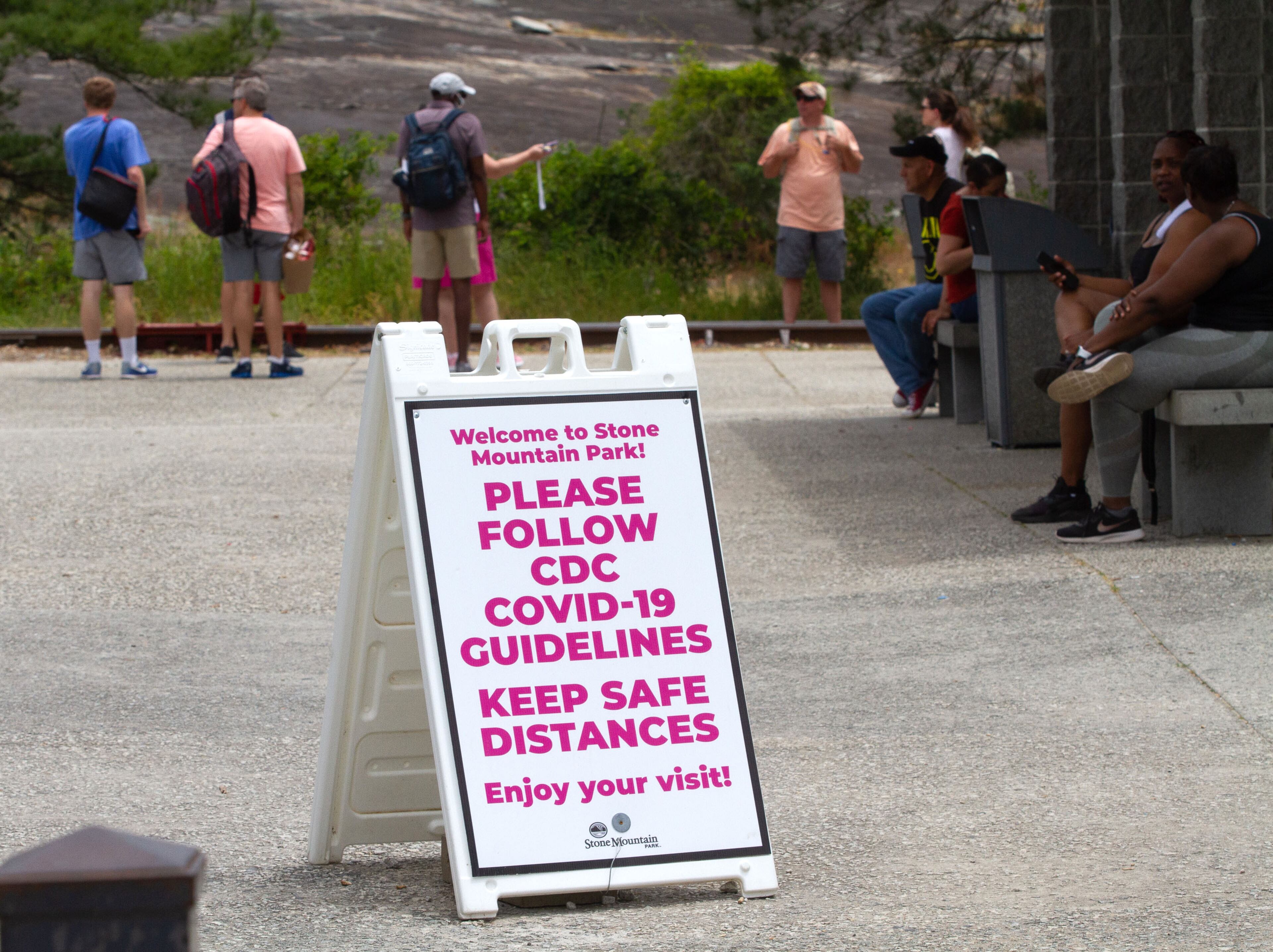 Signs reminding people to keep a safe distance apart are set up around Stone Mountain Park on Sunday, May 17, 2020. STEVE SCHAEFER FOR THE ATLANTA JOURNAL-CONSTITUTION
