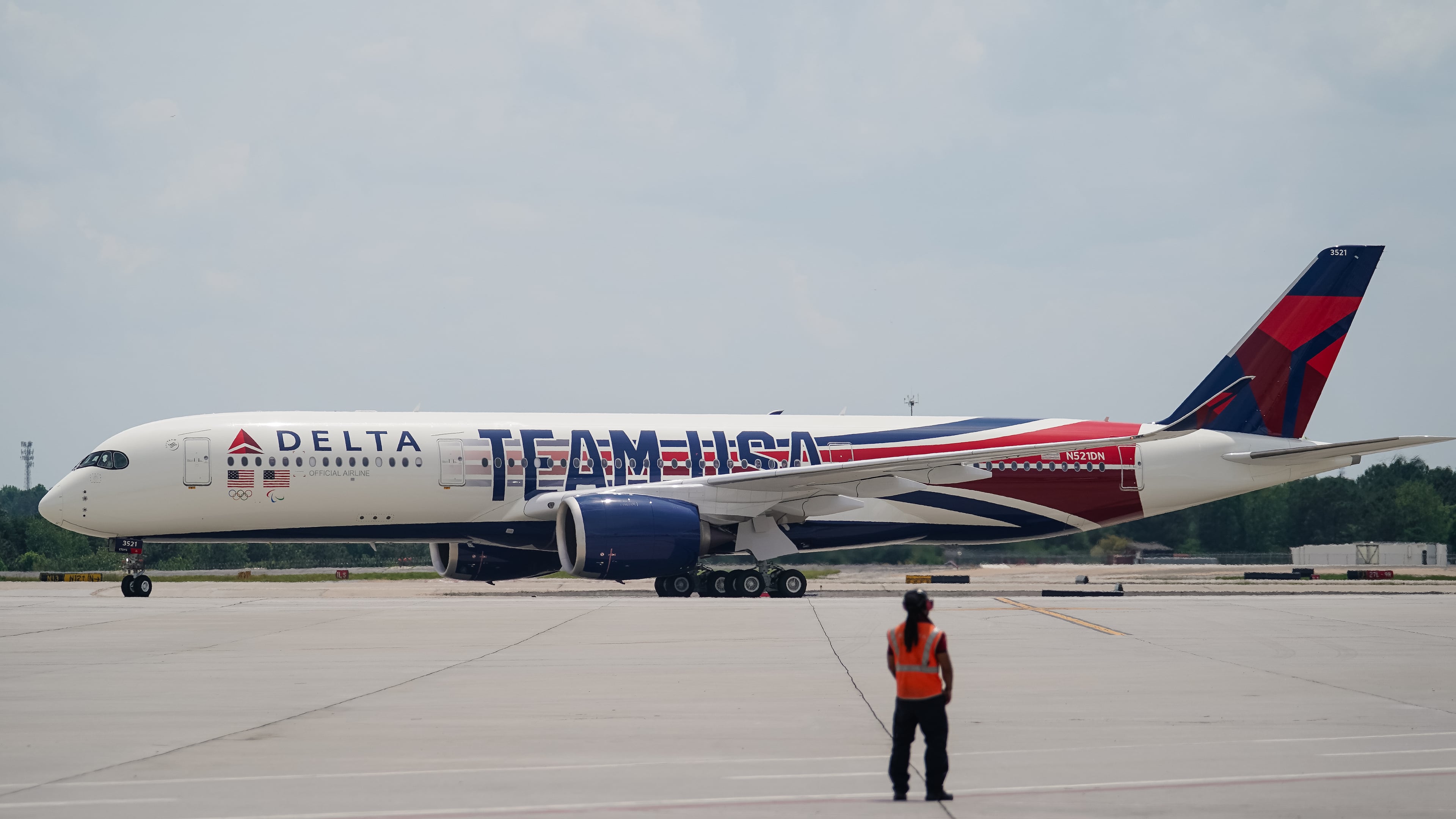 A Delta ramp agent looks at an Airbus A350 decorated in a new Team USA livery celebrating the Paris Olympics as it lands at Hartsfield-Jackson Atlanta International Airport on Friday, May 3, 2024. (Elijah Nouvelage for The Atlanta Journal-Constitution)