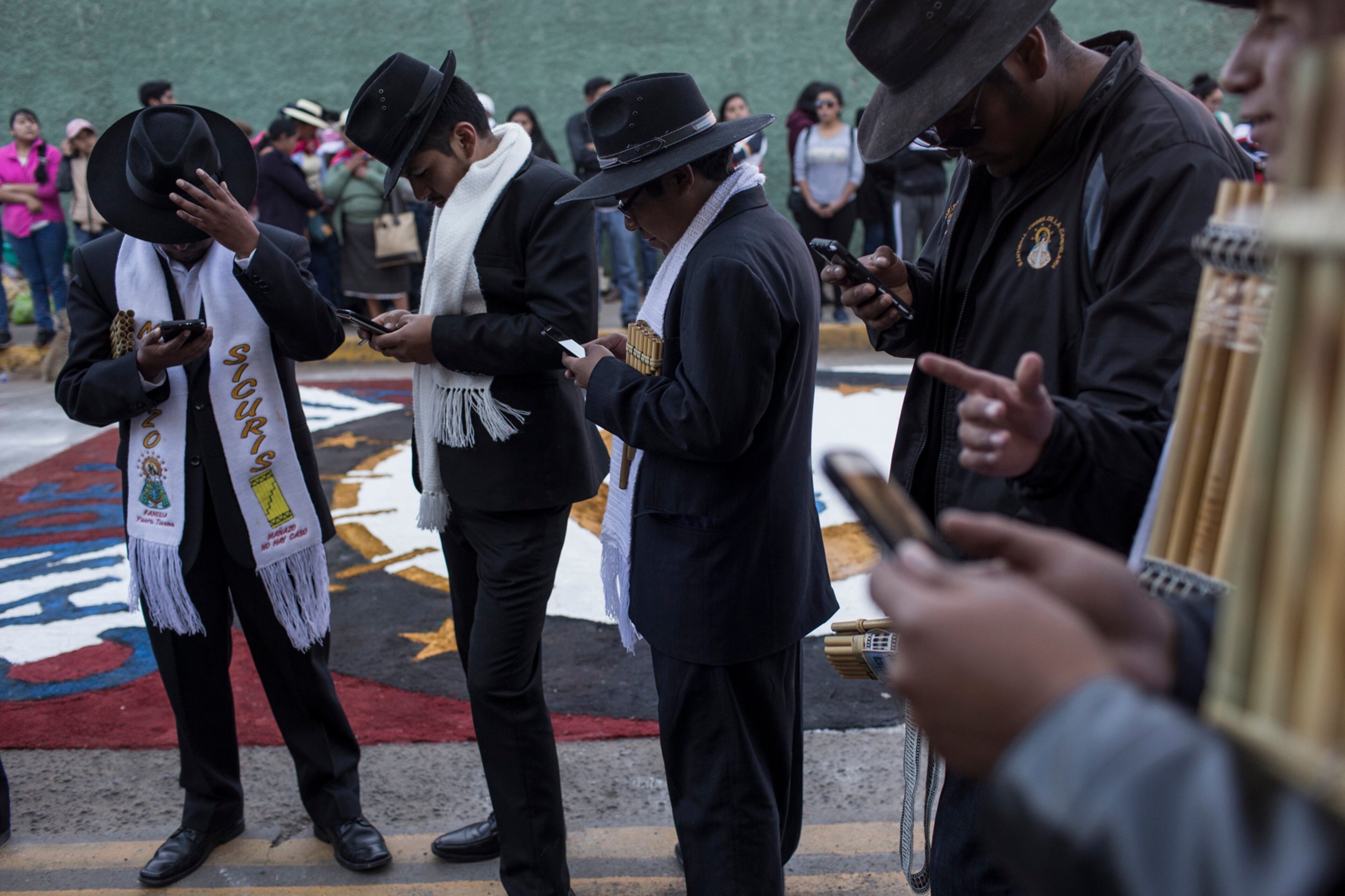 Musicians check their cell phones during a pause in the procession celebrating the feast day of the Virgin of Candelaria, in Puno, Peru, Thursday, Feb. 2, 2017. (AP Photo/Rodrigo Abd)