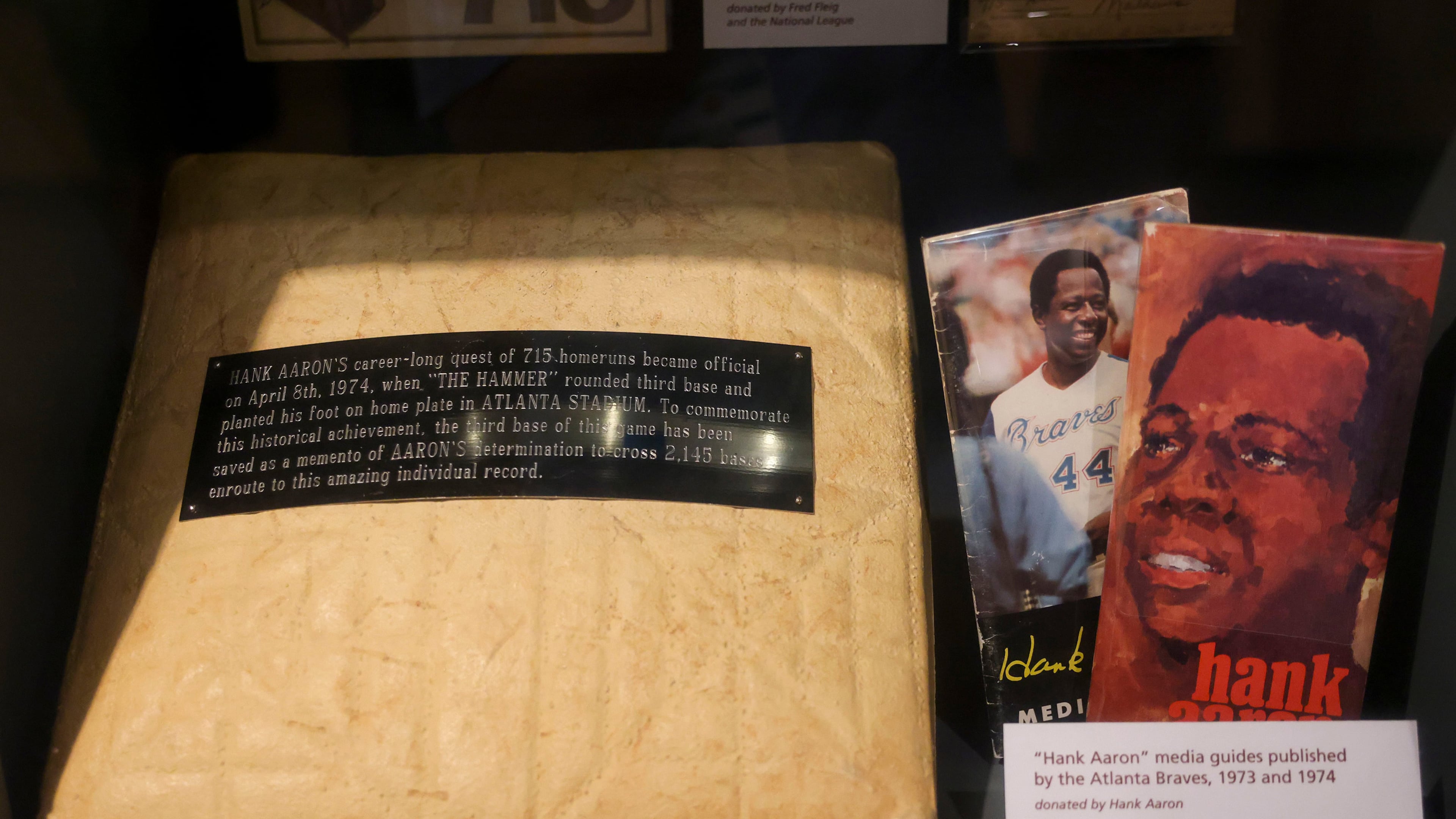 This is third base that Hank Aaron stepped on after he hit home run No. 715 on April 8, 1974, at Atlanta Stadium, shown in the exhibit, "Hank Aaron: Chasing The Dream," at the National Baseball Hall of Fame, May 23, 2024, in Cooperstown, New York. Also pictured are media guides from the Atlanta Braves from 1973 and 1974. (Jason Getz/The Atlanta Journal-Constitution/TNS)