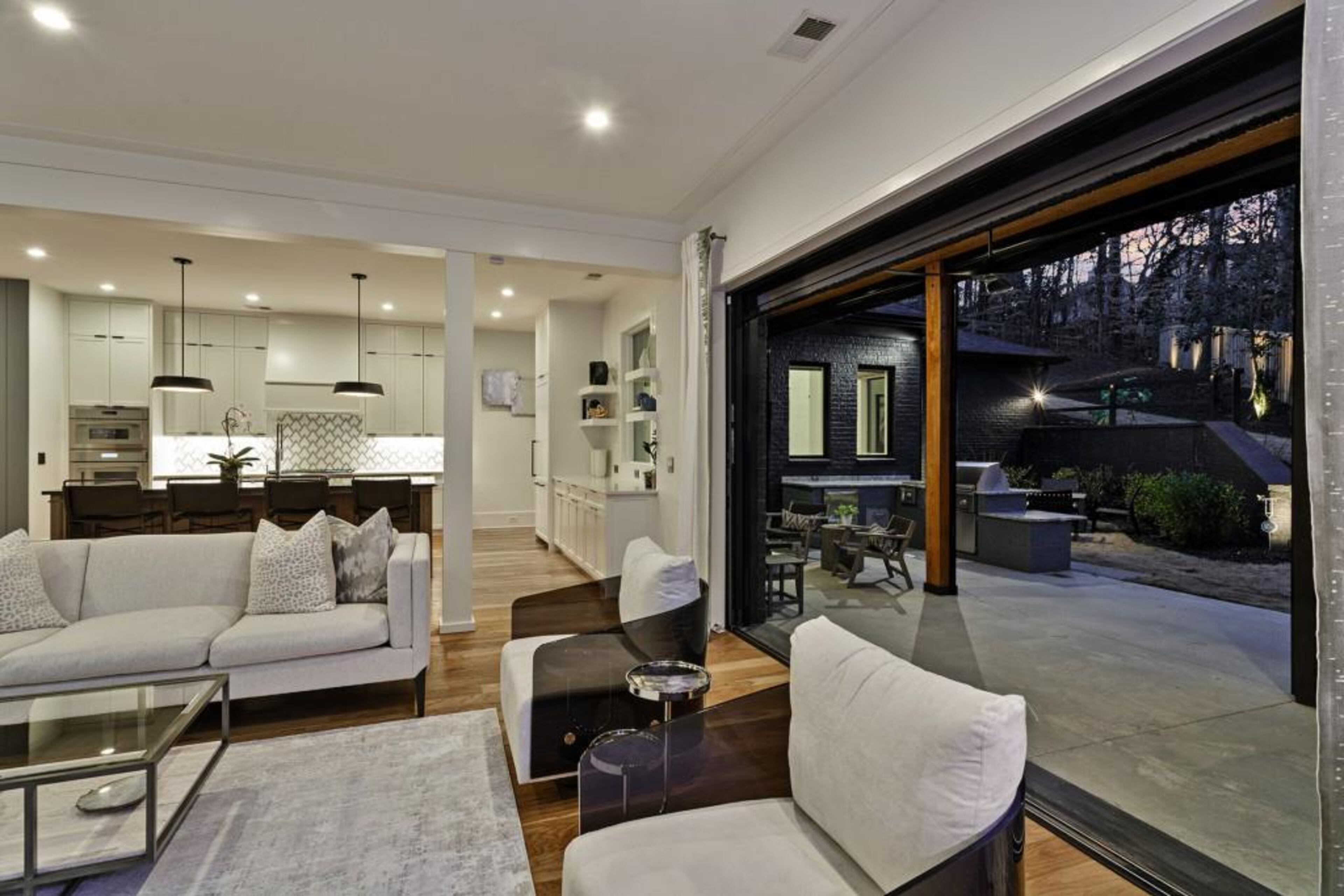 Kitchen opens to fireside great room featuring oversized glass nano doors that create a seamless transition into covered outdoor living space.