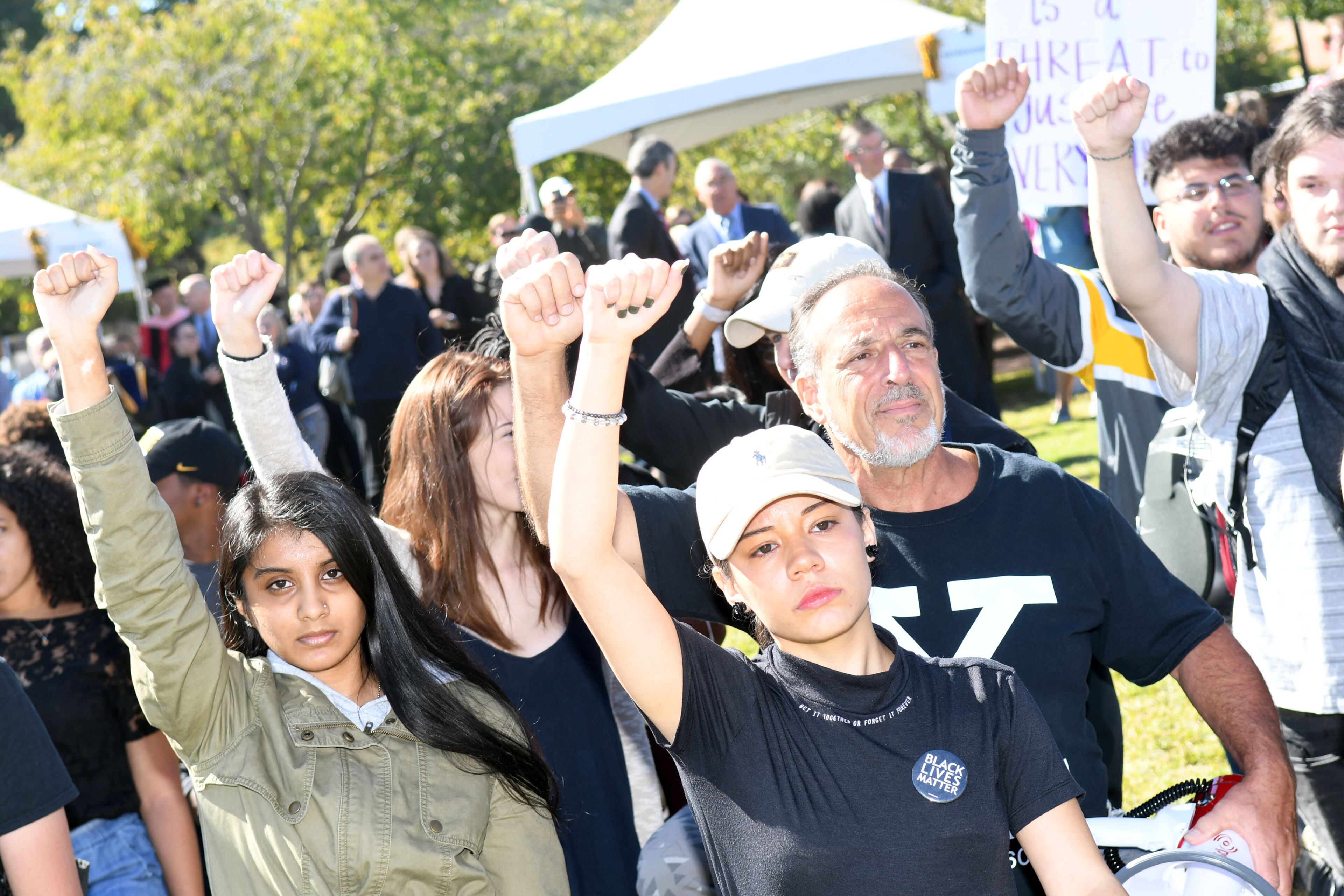 Alexa Vaca, a junior, majoring in political science, (middle) raises her arm with her fellow protesters take a knee at KSU on October 19, 2017. A group of Kennesaw State University students are protesting in support of the KSU cheerleaders who want to take a knee in protest of police brutality during the national anthem . (Rebecca Breyer)